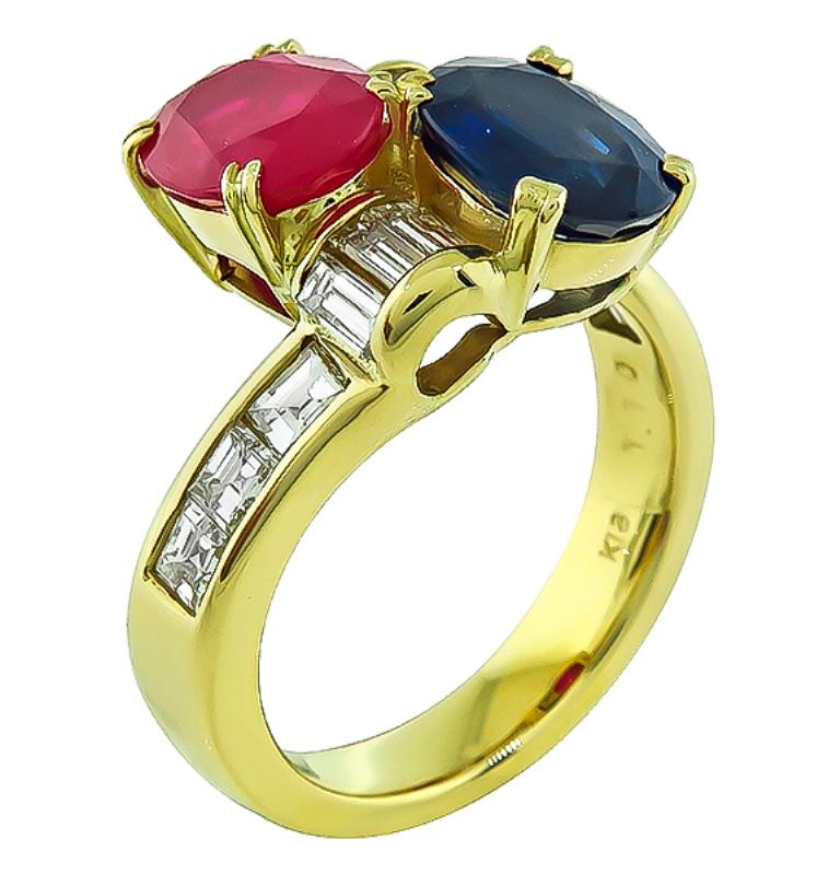 This elegant 18k yellow gold ring is set with lovely oval cut ruby and sapphire that weighs 1.85ct and 1.71ct respectively. The sapphire and ruby are accentuated by sparkling baguette and carre cut diamonds that weigh 1.10ct. graded G-H color with