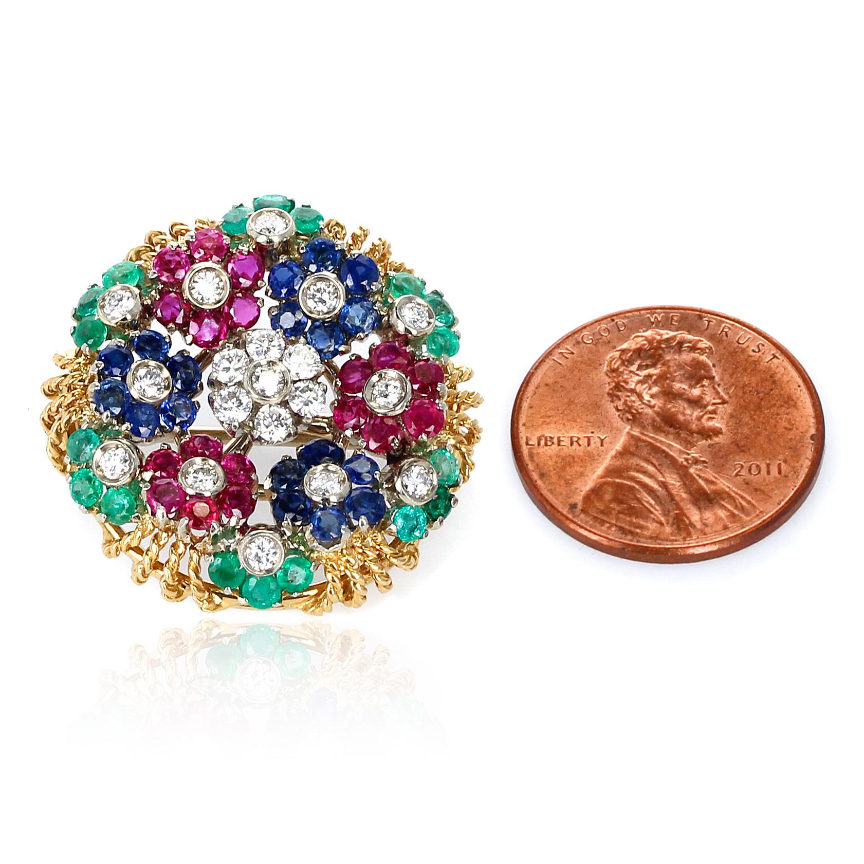A Ruby, Sapphire, Emerald and Diamond Circular Floral Design Brooch made in 18 Karat Yellow Gold. The diameter of the brooch is 1 inch. The middle flower, with the diamonds, spins. 
