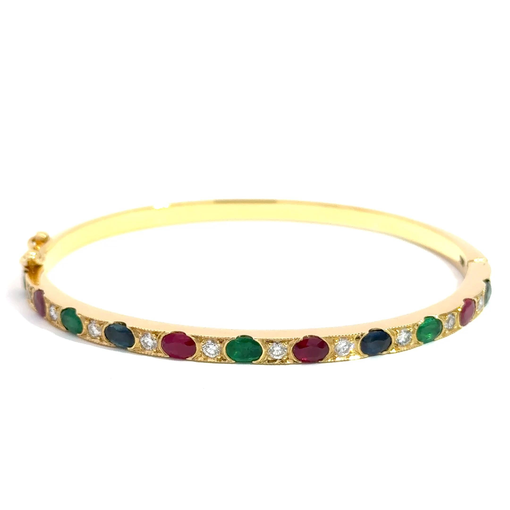 Expression audacieuse et vibrante d'une élégance intemporelle, ce bangle exquis présente un pot-pourri coloré de pierres précieuses serties dans un riche or jaune 18 carats. Avec 2,50 carats de rubis vifs, 2,00 carats de saphirs d'un bleu profond et