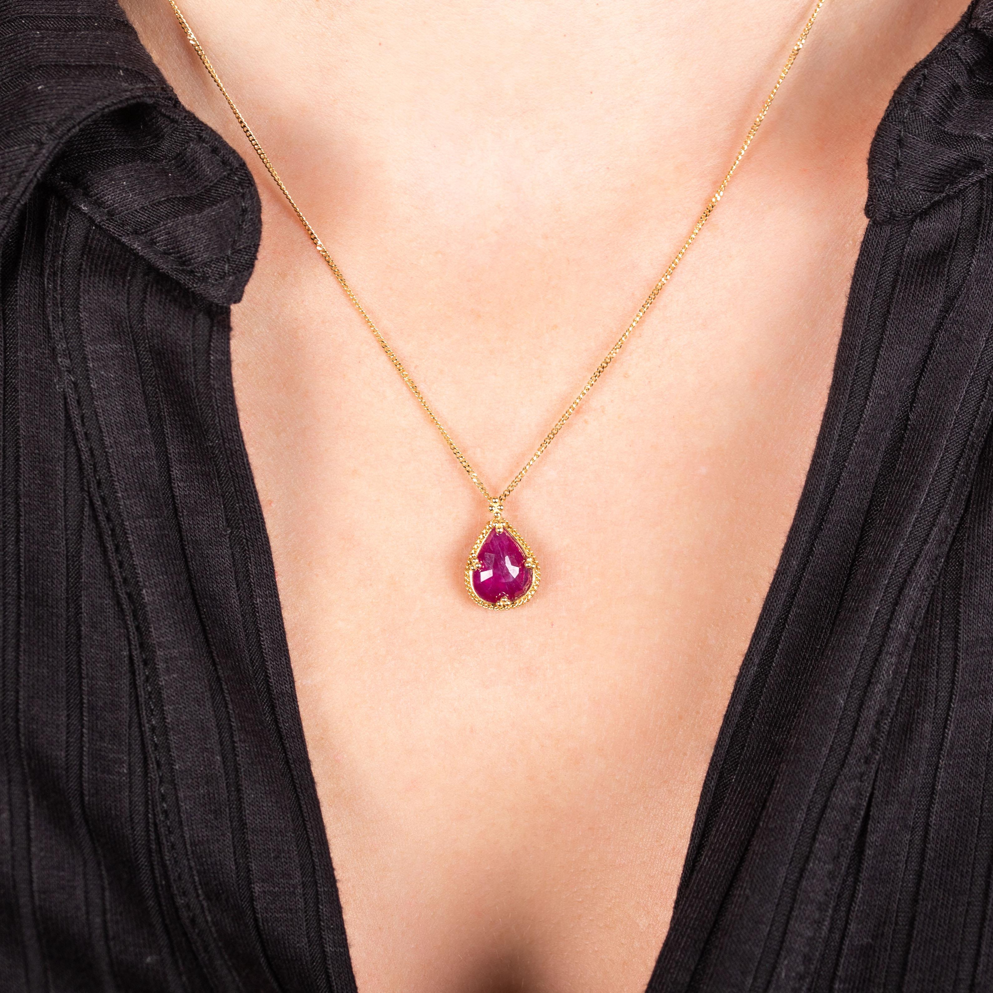 The faceted surface of this stunning, teardrop Ruby reflects light like morning dew drops on a crimson rose petal. This charming gemstone is set in a handmade gold bezel with braided detail and suspended from a gold chain. One of a kind.

Technical