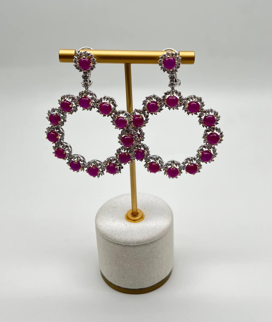 Eleganza con questi splendidi orecchini in oro bianco 18 carati, con vibranti rubini rosa cabochon da 27 carati.

L'intricato design è accentuato dalla brillantezza dei diamanti bianchi da 6 carati di peso totale, che creano un contrasto