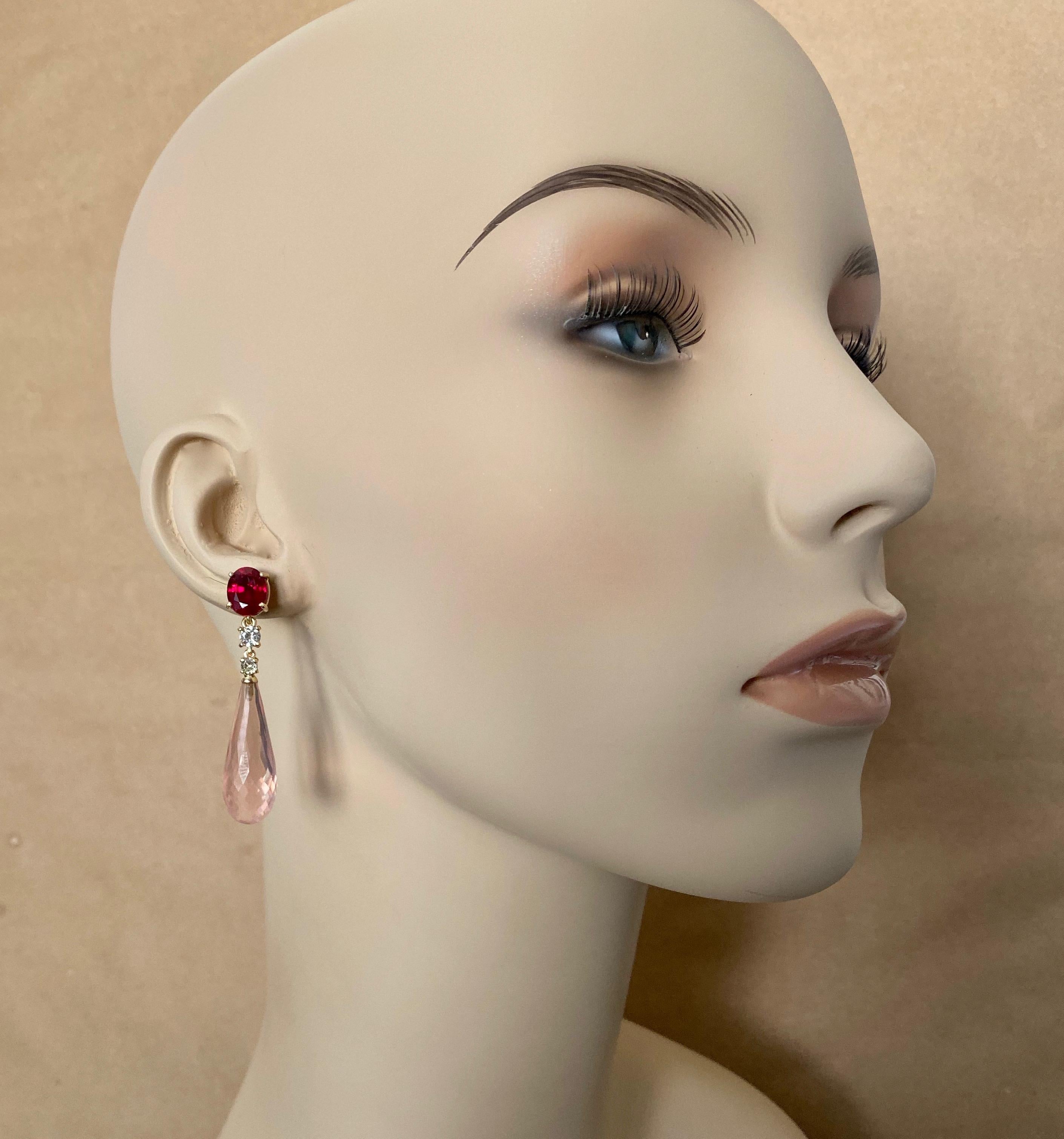 Rubies (origin: Karur, India) are showcased in these classically elegant dangle earrings.  The rubies are a pure, vibrant red color and are well cut and polished.  They are complimented by white diamonds.  Finishing the composition are rose quartz