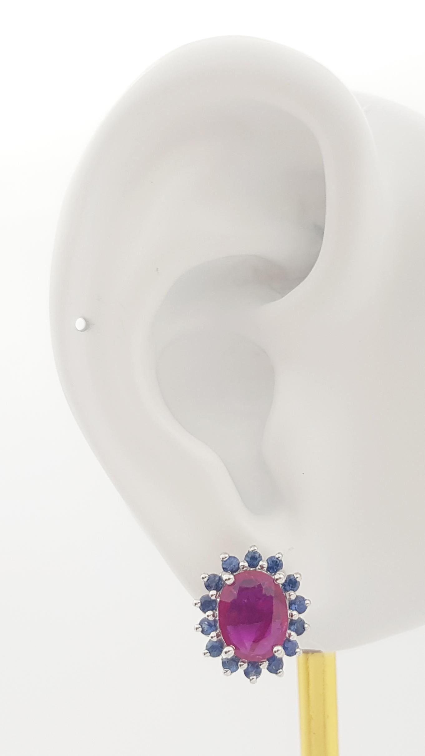 Boucles d'oreilles en or blanc 14K serties de rubis 2.74 carats et saphir bleu 0.88 carat

Largeur : 1.2 cm 
Longueur : 1.3 cm
Poids total : 6,08 grammes


