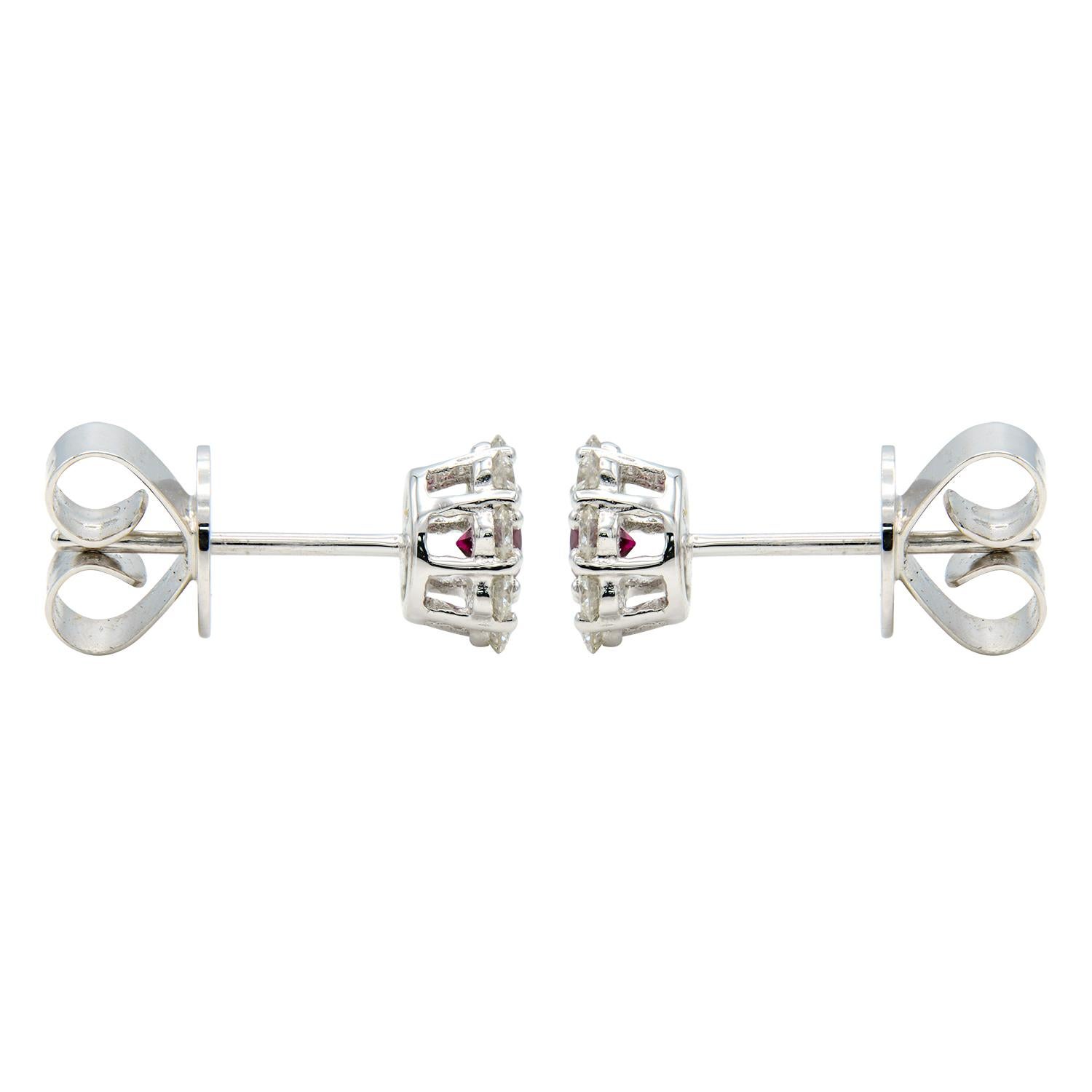 Ces magnifiques boucles d'oreilles sont composées d'un rubis au centre, entouré de 8 diamants de couleur VS2, G. Les rubis totalisent 0,24 carat et les diamants 0,39 carat. Les pierres sont serties dans 1,8 gramme d'or blanc 18 carats et sont dotées