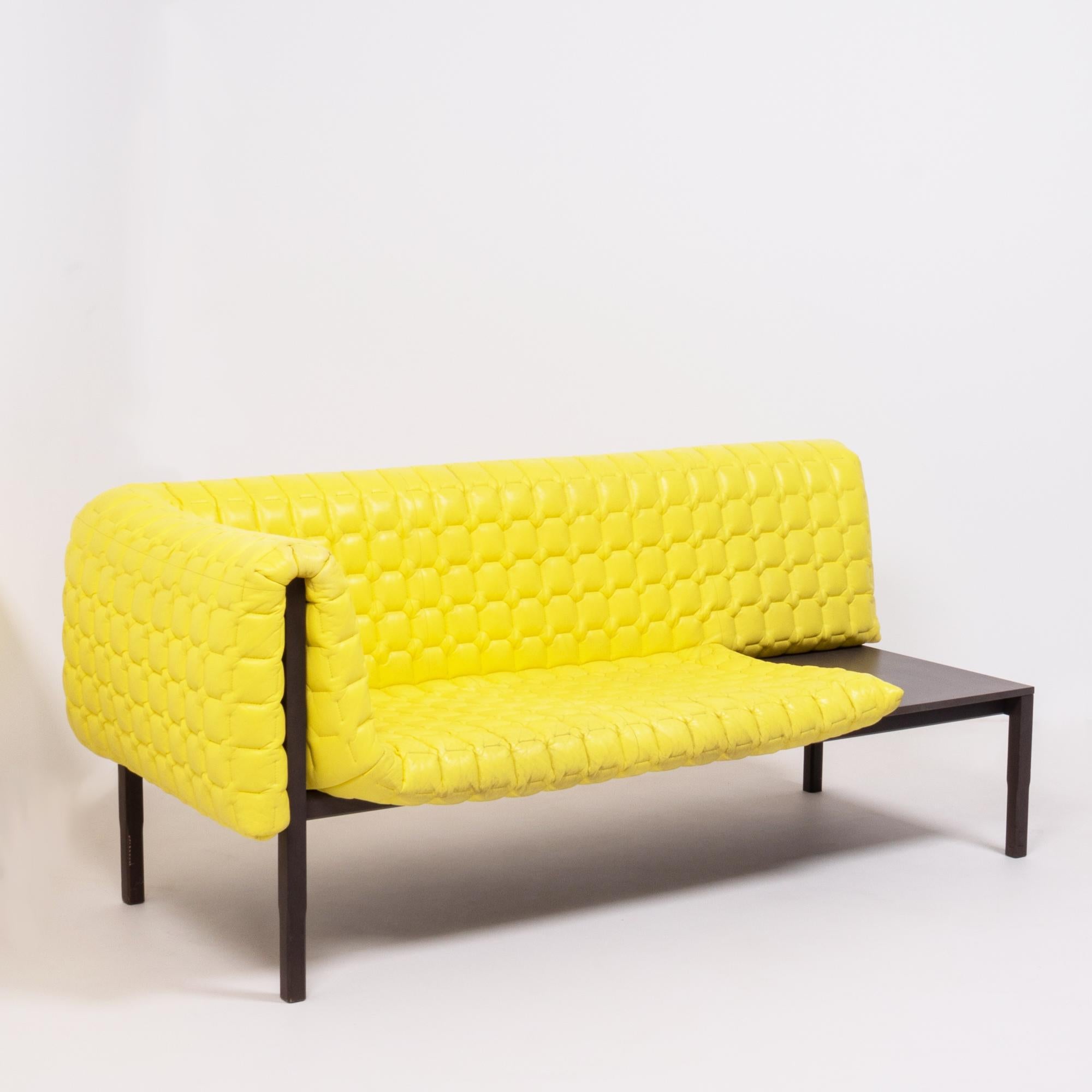 Originally designed by Inga Sempé for Ligne Roset in 2010, the Ruché sofa is a bold and bright piece of design.
This one arm sofa model is constructed with a beech wood frame stained in dark grey and features a contrasting yellow quilted leather