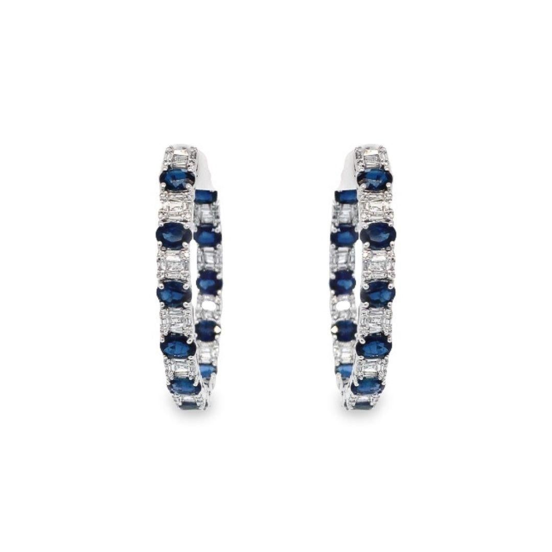 The 18k white gold hinged latch-back hoops feature an alternating pattern of 5.72 carats of oval-shaped blue sapphires and 1.01 carats of diamonds. The diamonds are composed of a mosaic of baguette diamonds surrounded by a halo of round diamonds,