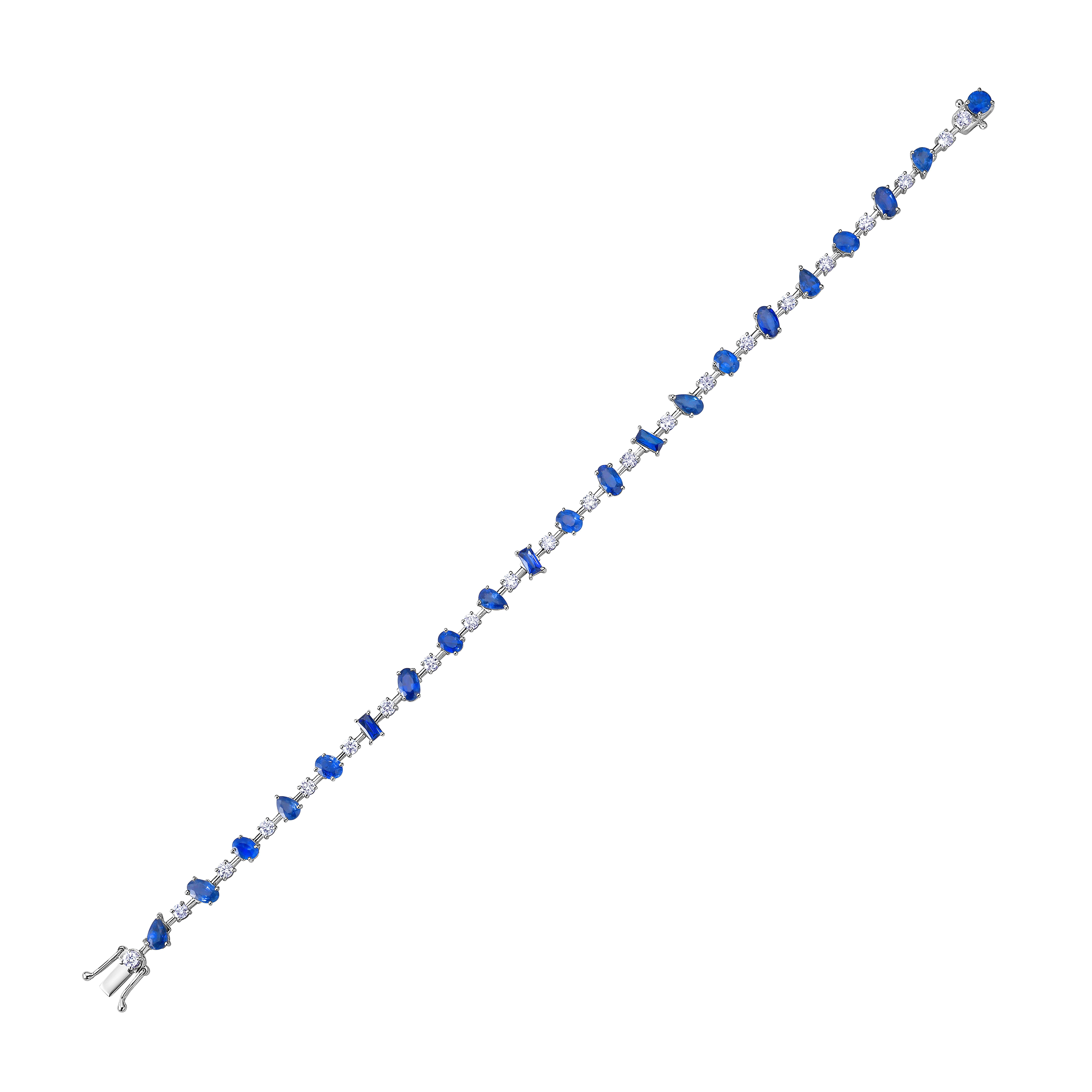 This 18k white gold knife-edge bracelet features an alternating pattern of mixed-shape blue sapphires and brilliant diamonds, secured with button prongs. It includes a box clasp with two figure-8 safety closures. The bracelet is designed to be worn