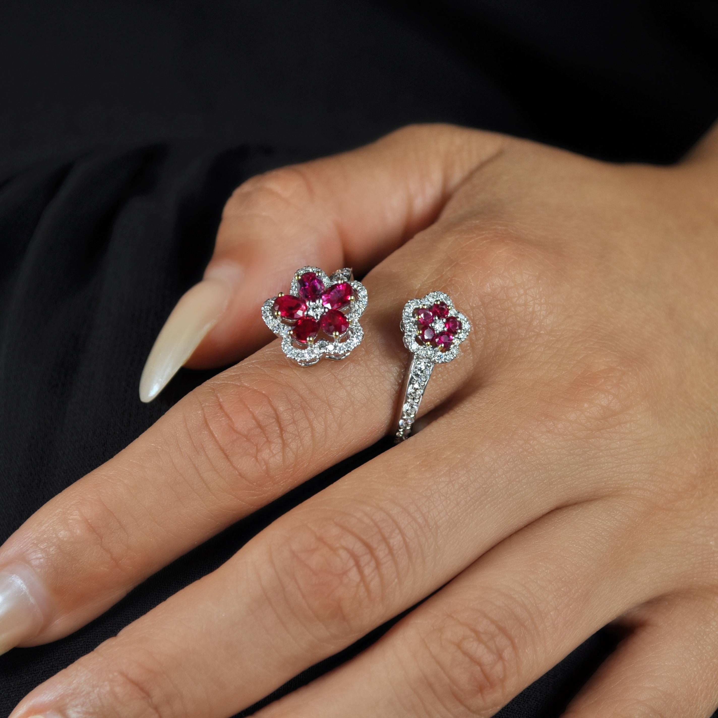 Caratterizzato da due fiori con rubini ovali e rotondi fissati con punte in oro giallo e da dettagli di diamanti rotondi lungo la fascia, questo anello bypass floreale in oro bianco 18 carati è una silhouette classica di gioielli con un tocco di