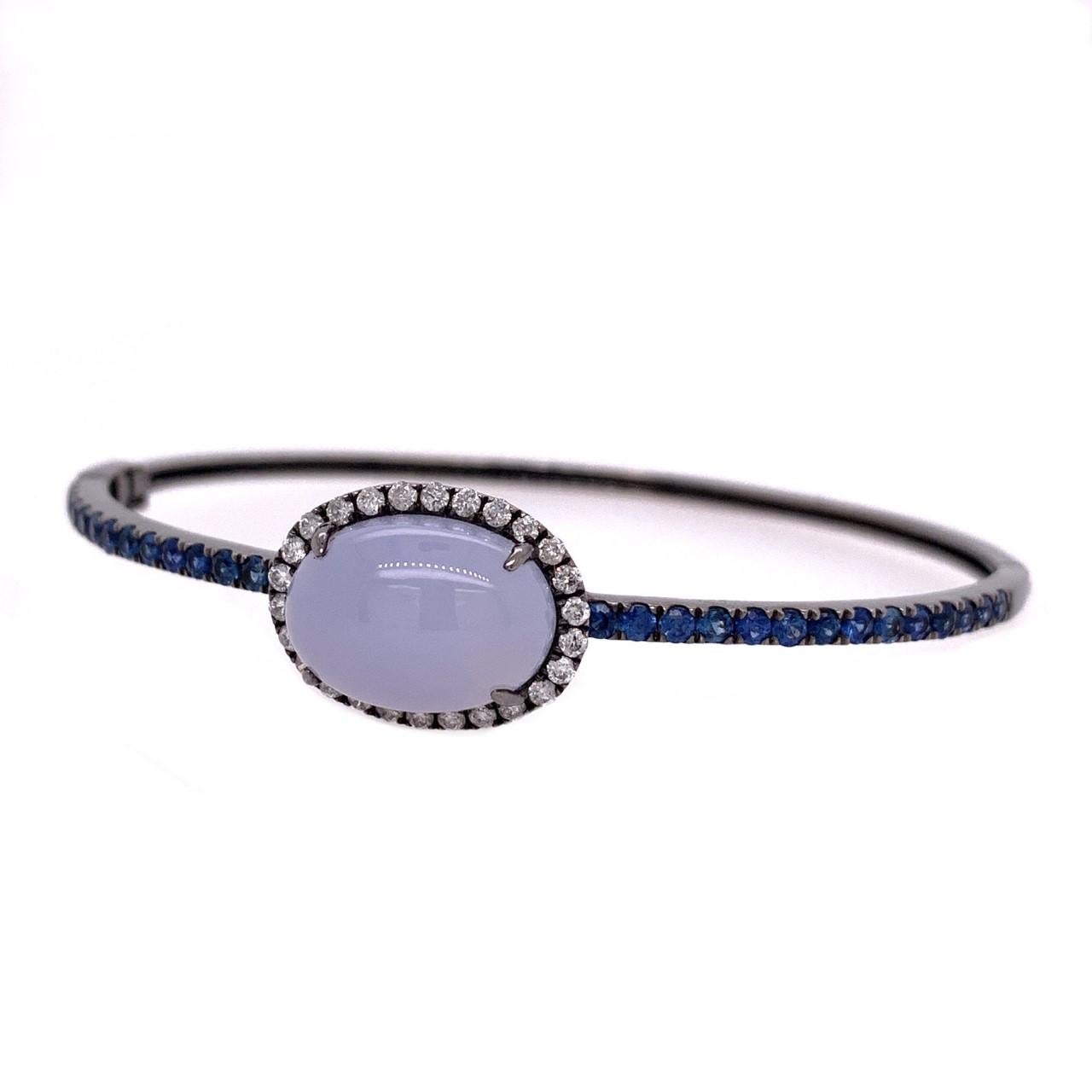Midnight Blue Collection

Enchanting Chalcedony cabochon with Diamond halo and Sapphire bangle in 18 karat black rhodium gold. 

Chalcedony: 6.79ct total weight.
Blue Sapphire: 1.11ct total weight.
Diamonds: 0.36ct total weight. 
All diamonds are