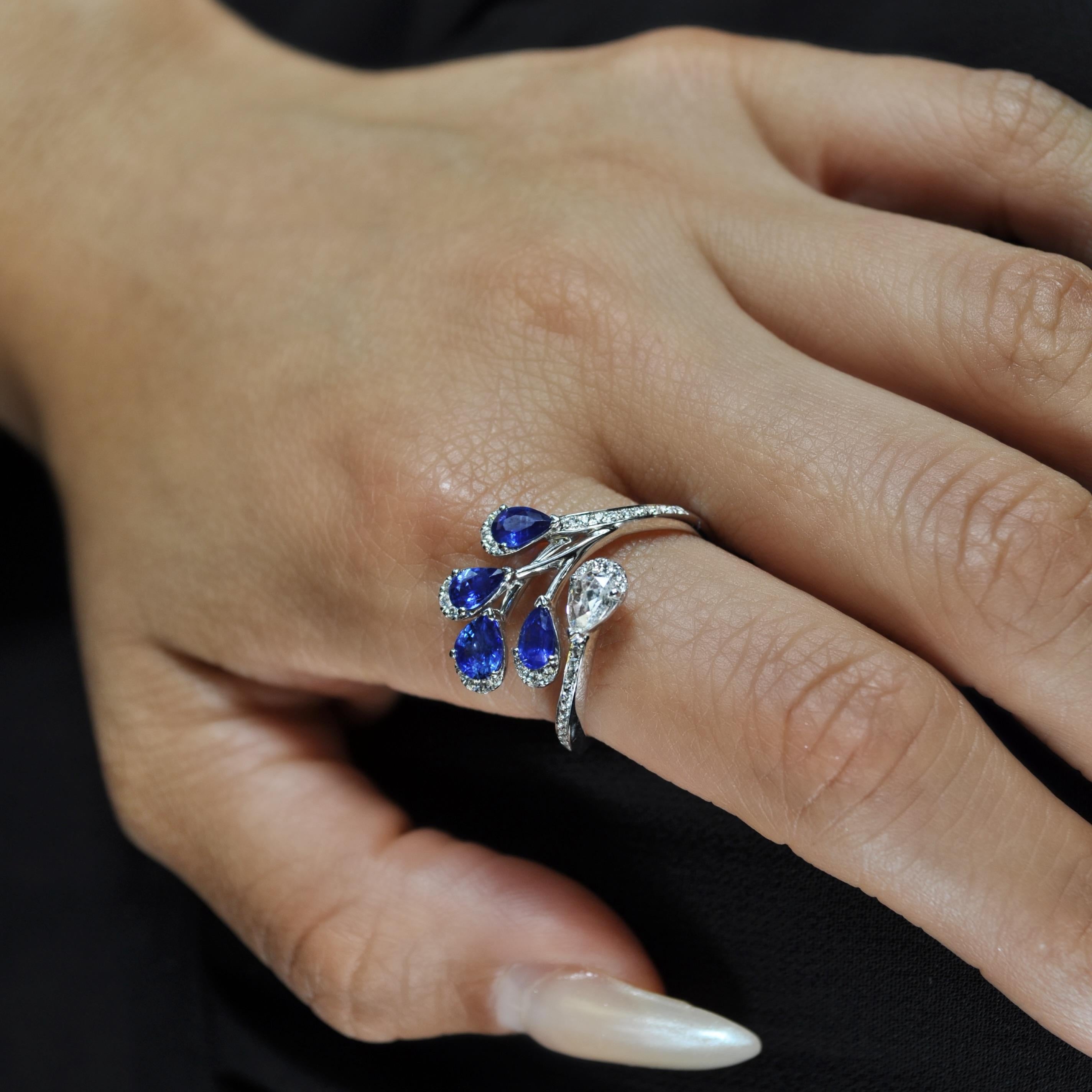 Dieser Bypass-Ring aus 18 Karat Weißgold besteht aus 1,28 Karat birnenförmigen blauen Saphiren, 0,40 Karat Diamanten im Brillantschliff, die die Blattmotive einfassen, und einem birnenförmigen Diamanten als unteres Blatt.

Blauer Saphir - 1.28