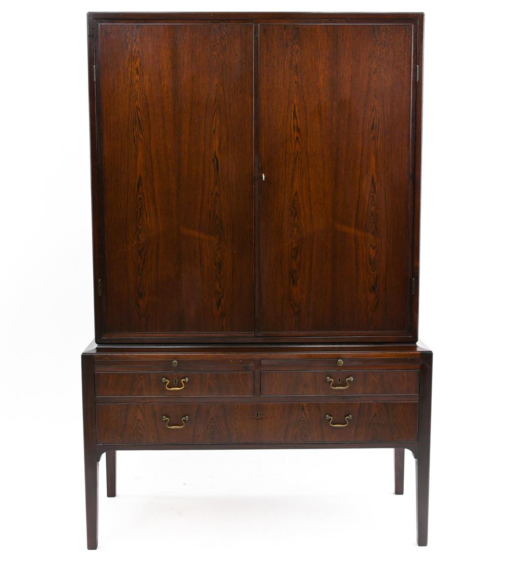 This rosewood cabinet by Rud Rasmussen is numbered on the back leg. This design is attributed to Kaare Klint and features cabinet doors with drawers underneath.