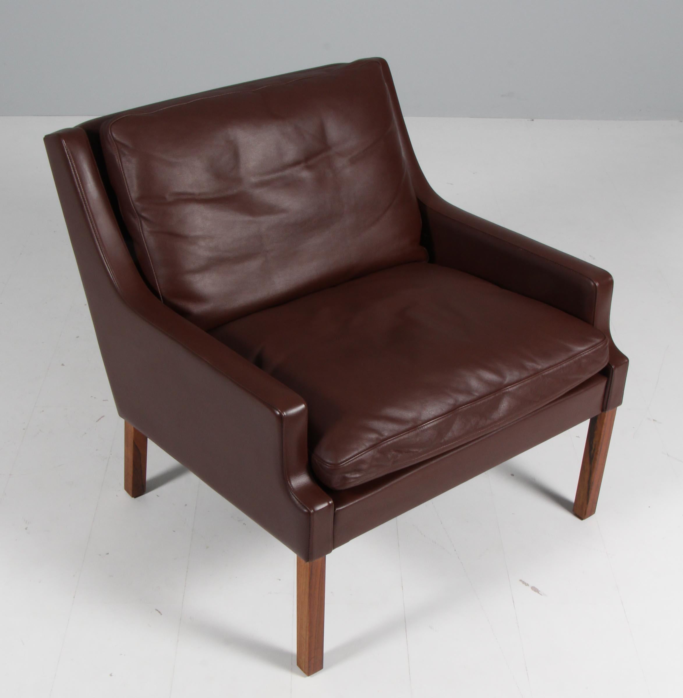 Rud Thygesen lounge chair with legs of rosewood.

Original duvet cushions with brown light patinated leather. 

Made by Thams.