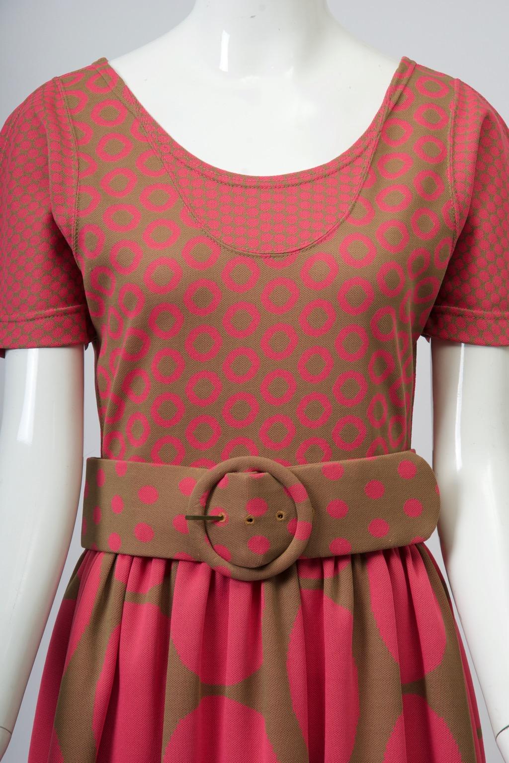 A great find, this Rudi Gernreich c.1970s dress is fashioned of polyester knit featuring a dot design in varying sizes in pink and olive, the bodice simulating a jumper and tee shirt form with scoop neck and short sleeves, each of contrasting small