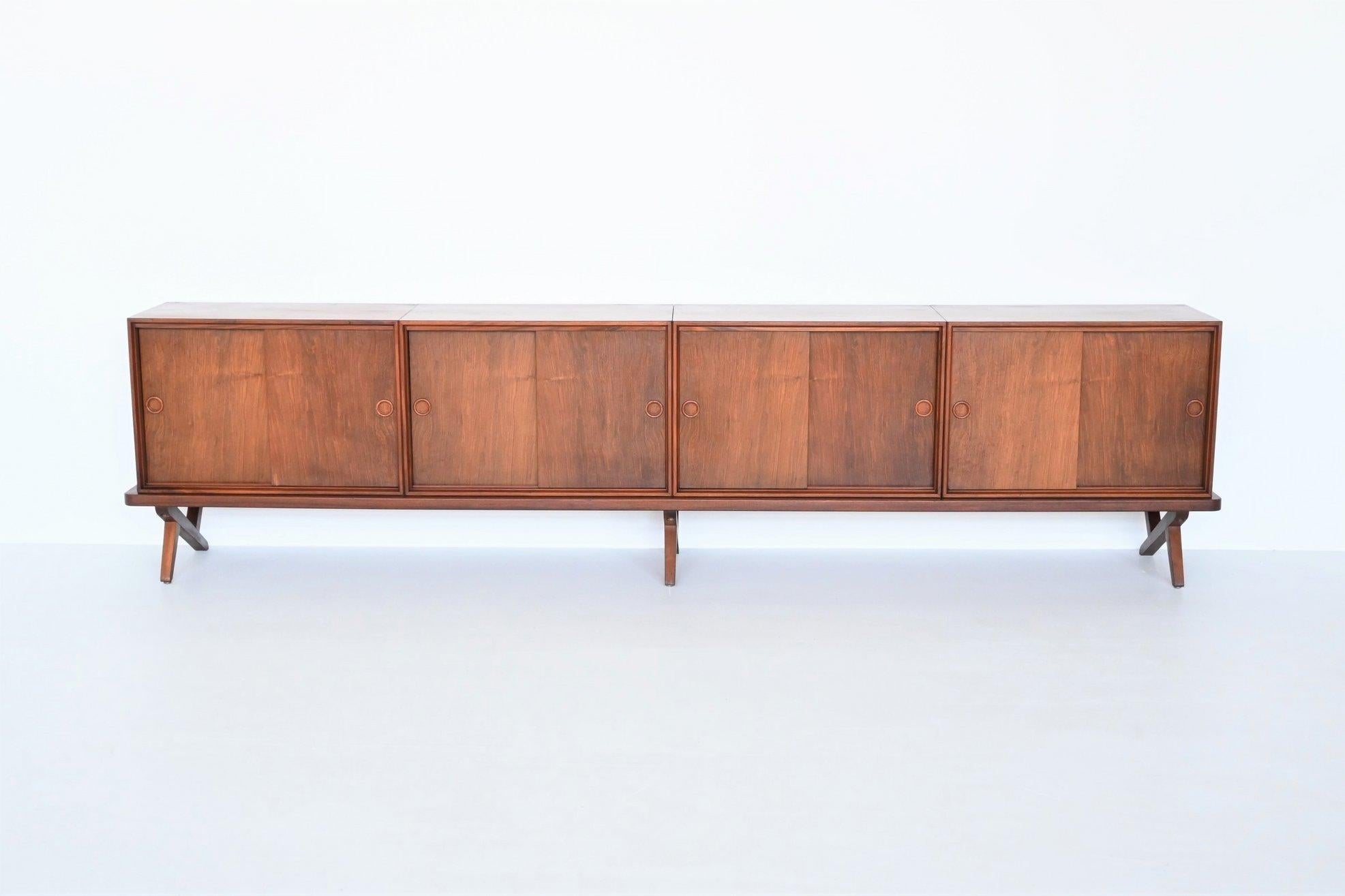 Beautiful shaped long sideboard designed by Rudolf Bernd Glatzel and manufactured by Fristho Franeker, The Netherlands 1955. This unique sideboard has four compartments, all with two sliding doors and a shelve each. This was designed as a modular