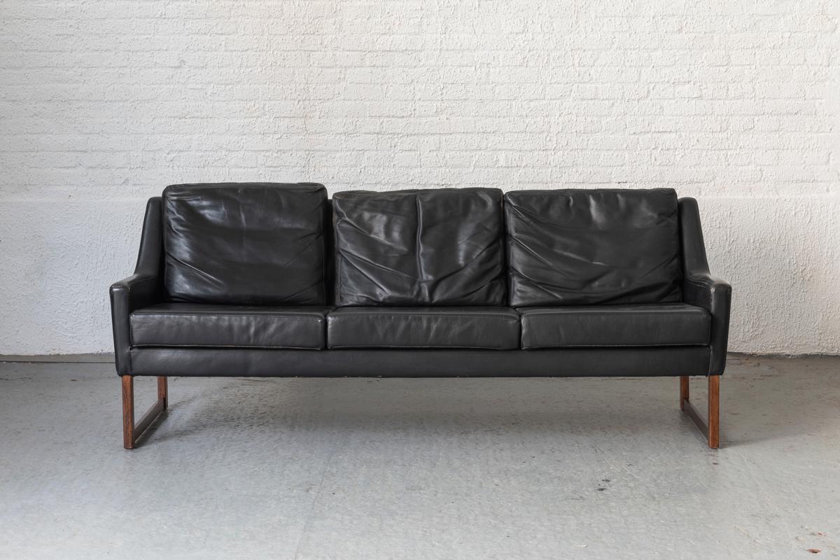 3-seater sofa designed by Rudolf Glatzel for Kill International, Germany, 1960s. The sofa features a solid wooden frame with a black leather upholstery. Some wear such as patinated corners. Overall in good condition. 

We also have a matching set of