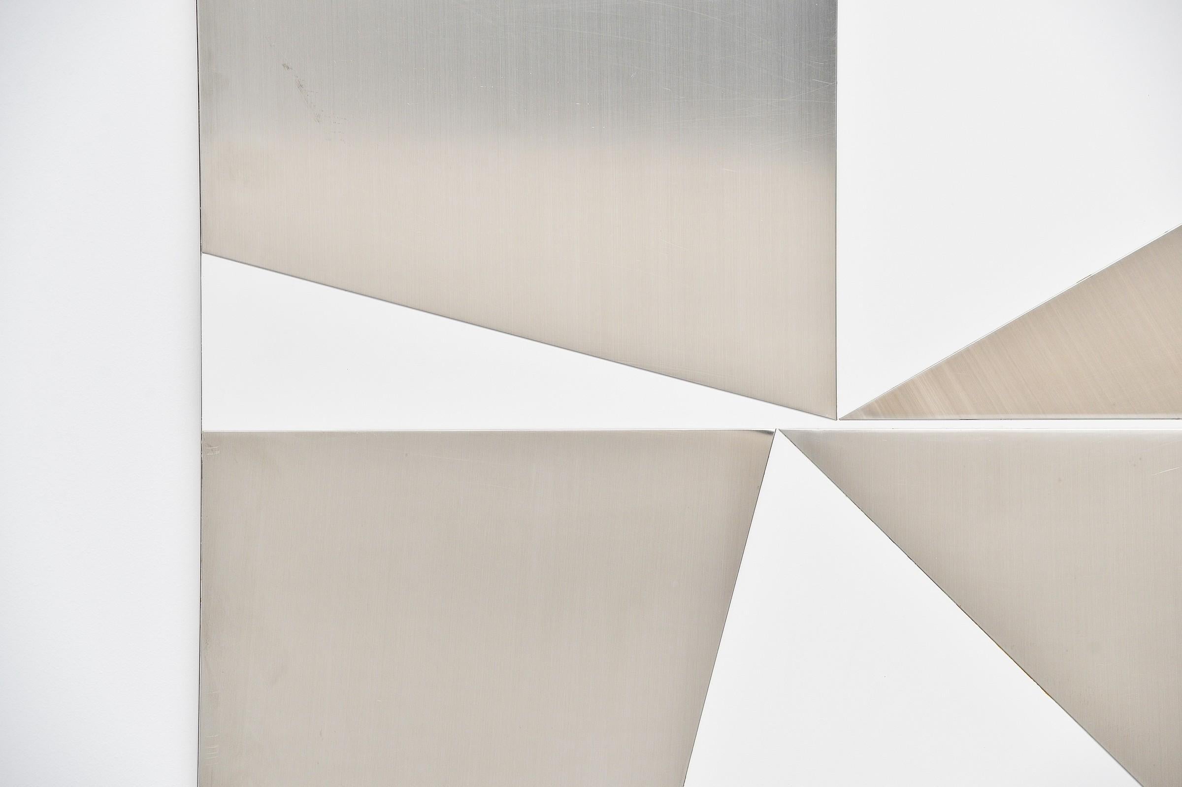 Large abstract modern triangles shaped stainless steel wall artwork designed by Rudolf Wolf and manufactured in his own atelier in 1972. This wall panel is made of white laminated board and has a stainless steel abstract configuration with triangle