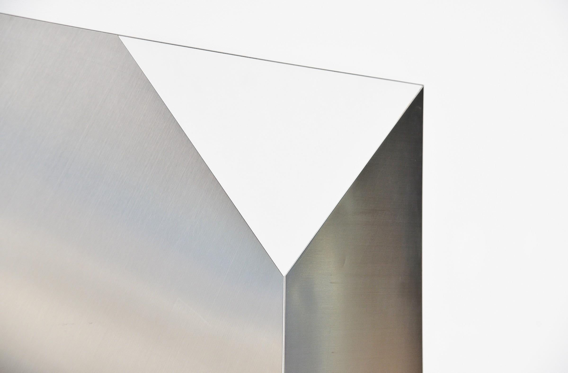 Large abstract modern shaped stainless steel wall artwork designed by Rudolf Wolf and manufactured in his own atelier in 1972. This wall panel is made of white laminated board and has a stainless steel abstract modern configuration on it. This
