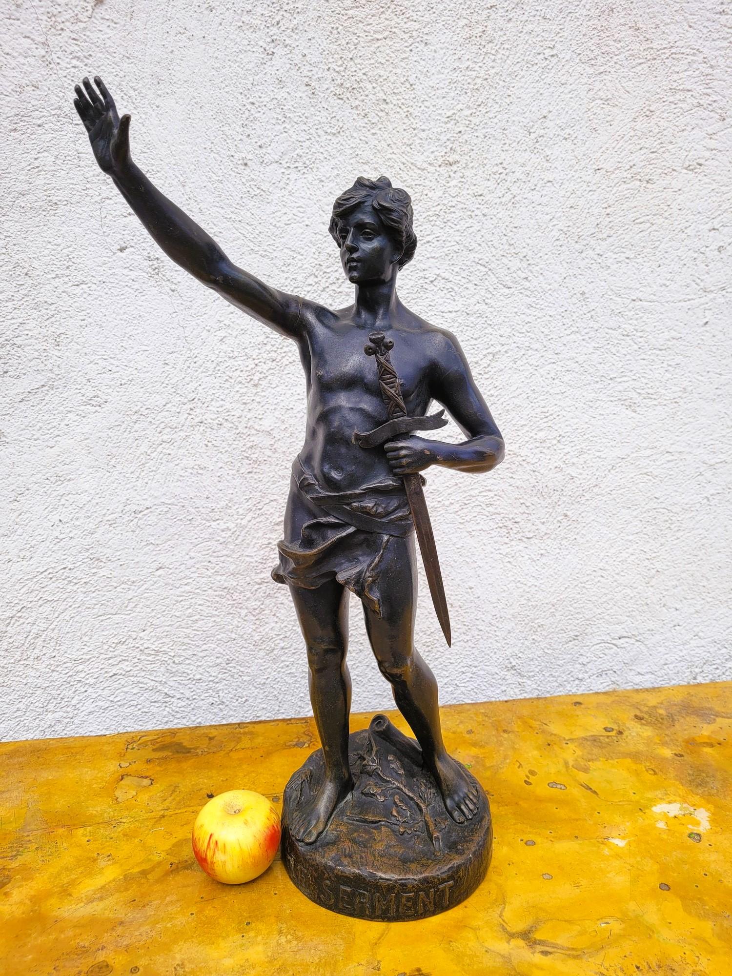 Il Giuramento: scultura in bronzo con patina marrone, raffigurante un giovane uomo, con la spada in mano, che presta giuramento.

La base rotonda è intitolata e firmata dall'artista: Oscar Ruffony. Scultore svizzero, ma attivo in Francia, è noto