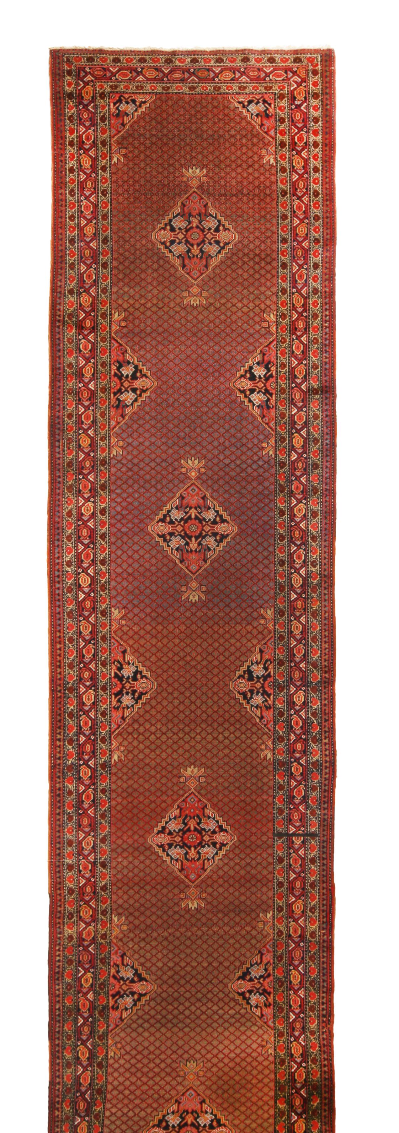 Originating from Persia between 1890-1900, this antique geometric-floral Persian runner is hand knotted in high-quality wool with distinct attention to a marriage of medallion and all-over field designs. The rich and varied portrait of rustic red