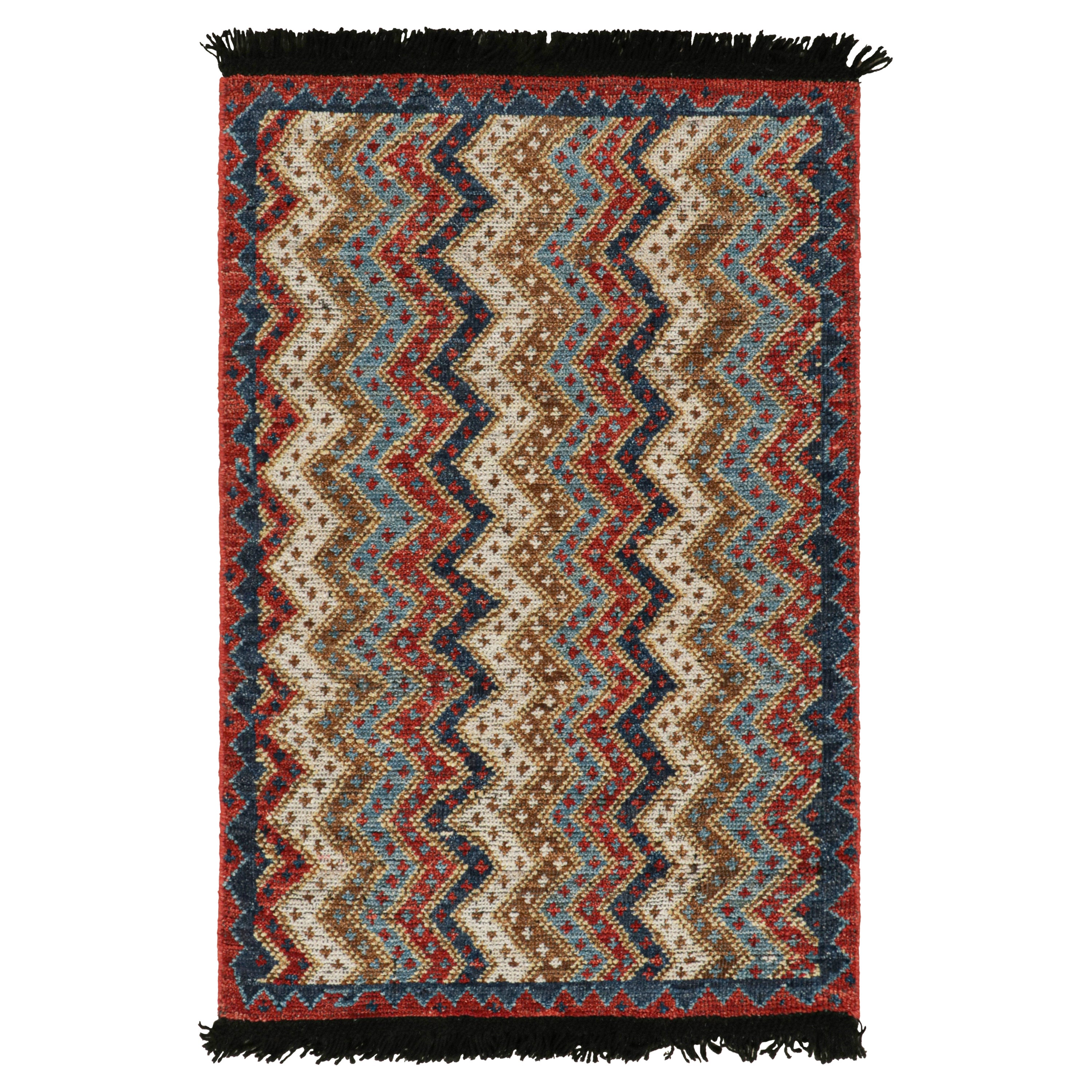 Rug & Kilim è un tappeto antico in stile tribale, con motivi chevronici rossi, blu e beige.