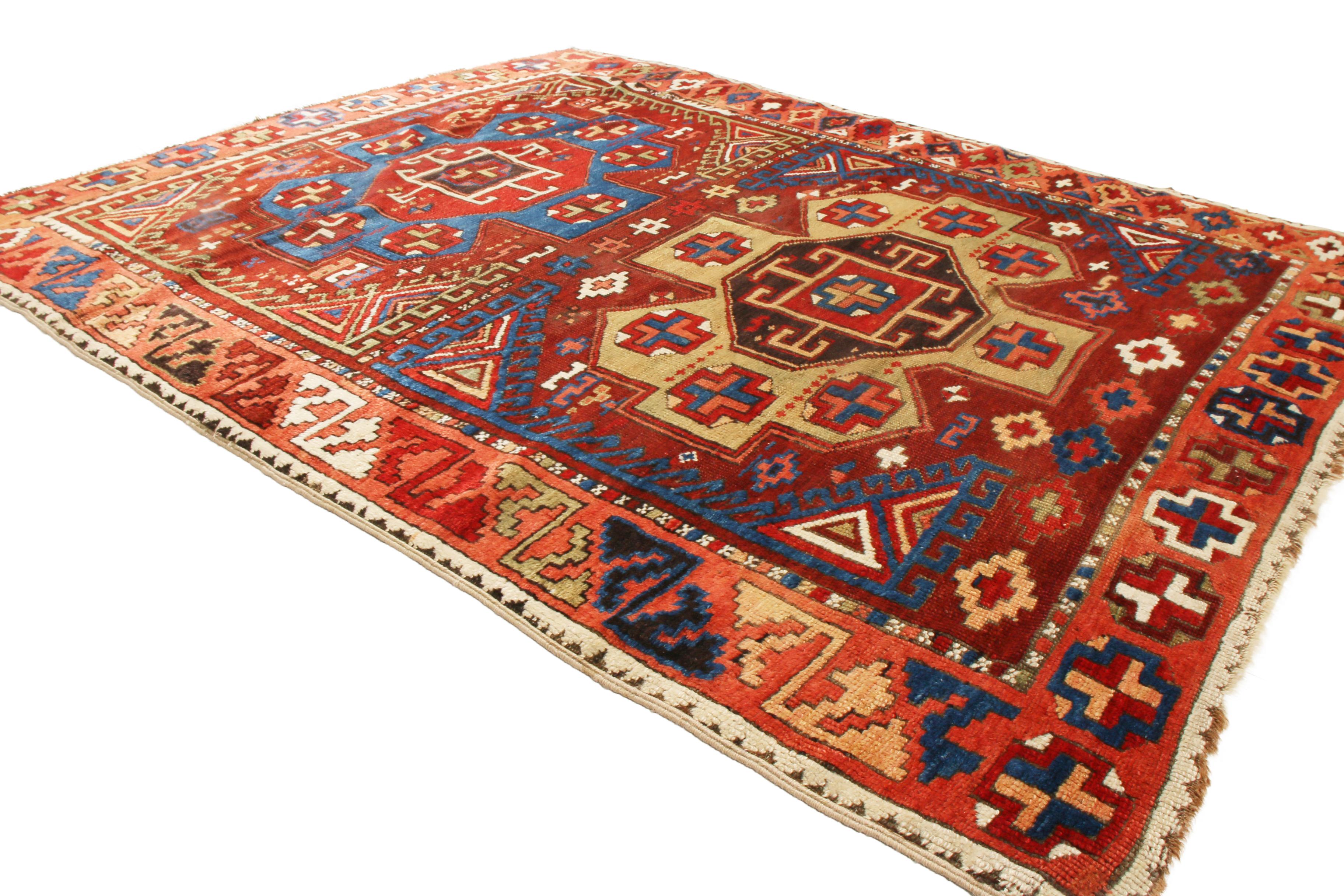 Originating from Turkey between 1900-1920, this antique traditional Yuruk rug features two distinct geometric medallions with centric Gul symbols in beige and blue against a rich burgundy red background. Unique to this piece is that just as the