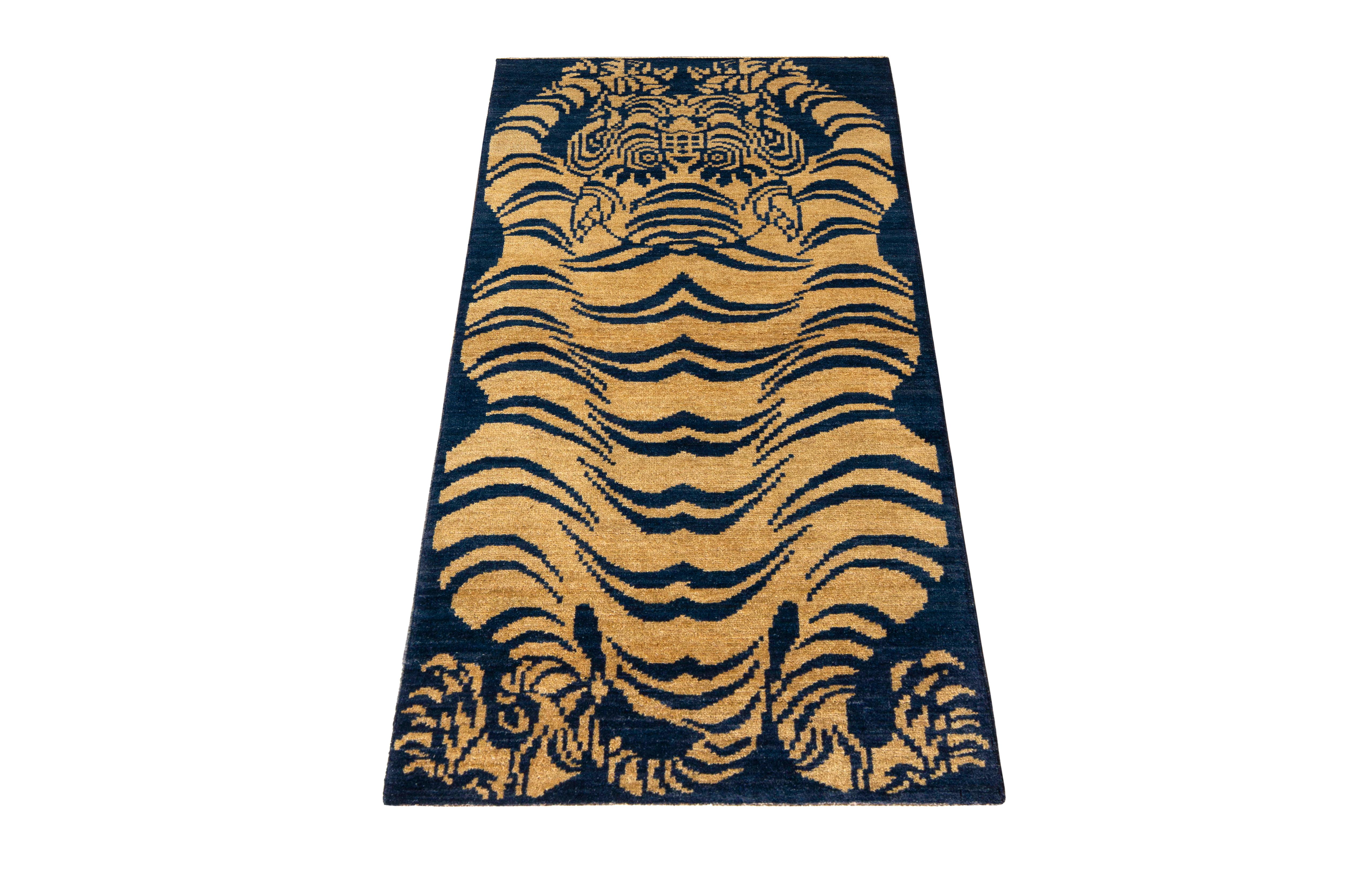 A 3 x 6 ode to celebrated tiger rug styles, from the latest collection by Rug & Kilim. Hand knotted in wool, enjoying rich shades of gold and blue in an almost positive-negative play with the pictorial pattern in meticulous detail. Exemplifying the