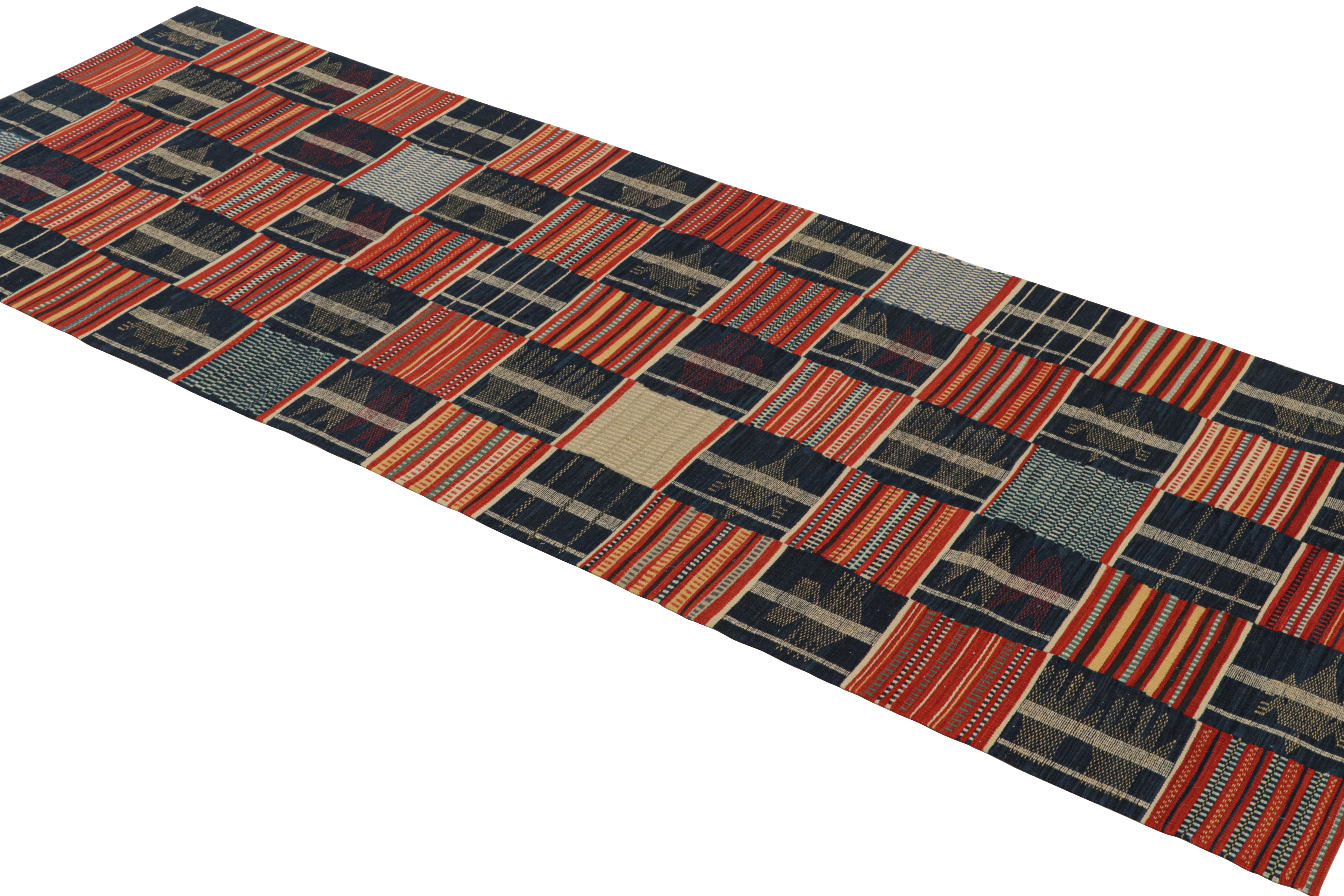 Originario della Cina, questo runner contemporaneo è annodato a mano con lana resistente e di alta qualità e raffigura un disegno patchwork del Ghana, con una serie di motivi protettivi a mano e a medaglione nei ricchi colori tribali blu navy,