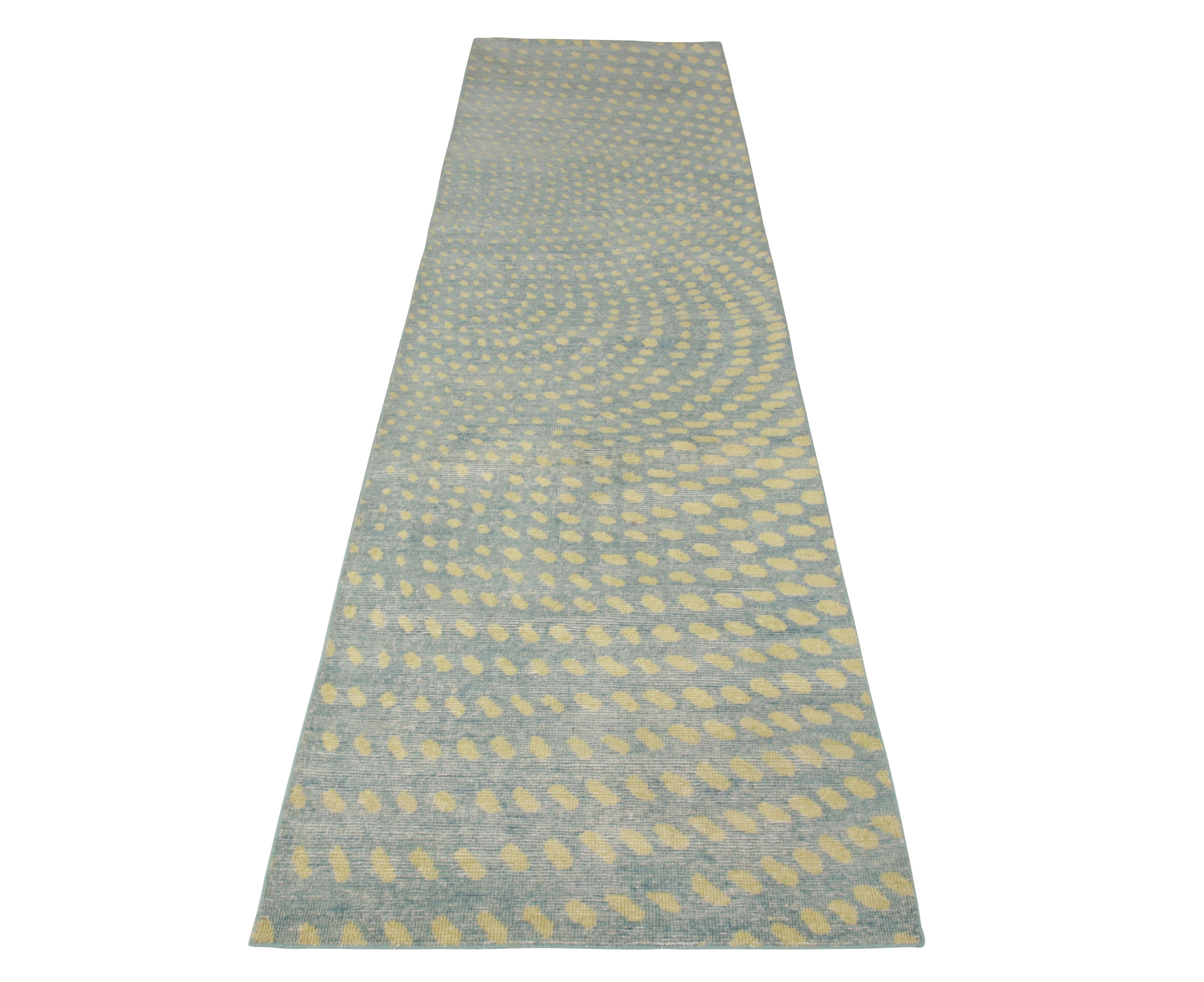 Noué à la main en laine, un accueillant chemin de table 3 x 12 disponible dans la collection Homage de Rug & Kilim. Cette pièce dégage une atmosphère estivale et lumineuse, avec des points jaunes qui dansent de façon ludique sur un fond bleu