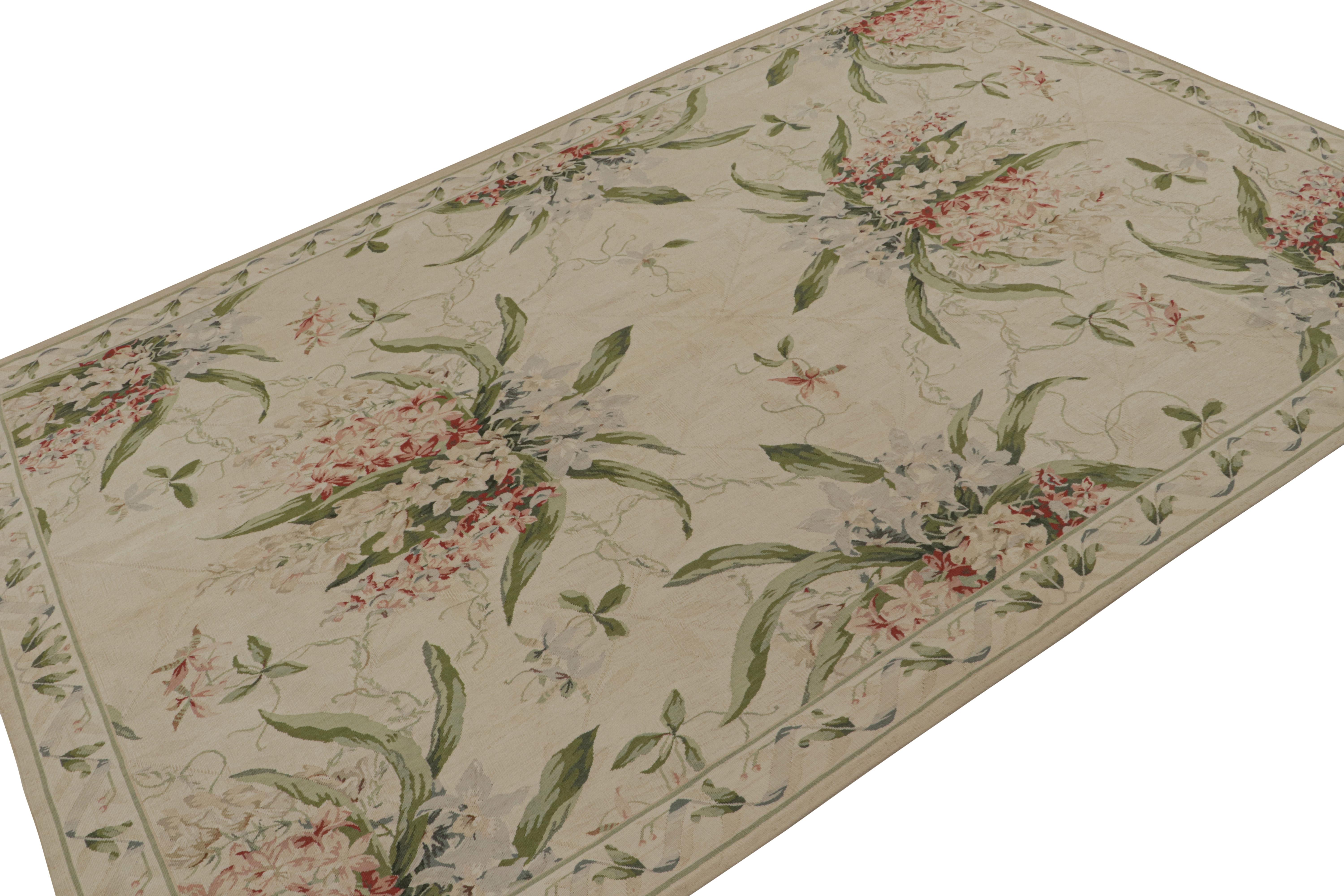 Anudada a mano en lana, esta alfombra europea Tudor de 6x9 en tejido plano de color beige presenta intrincados motivos florales en verde, rosa y otros tonos primaverales con un aspecto más tenue y suave, acorde con la elegancia y sofisticación de