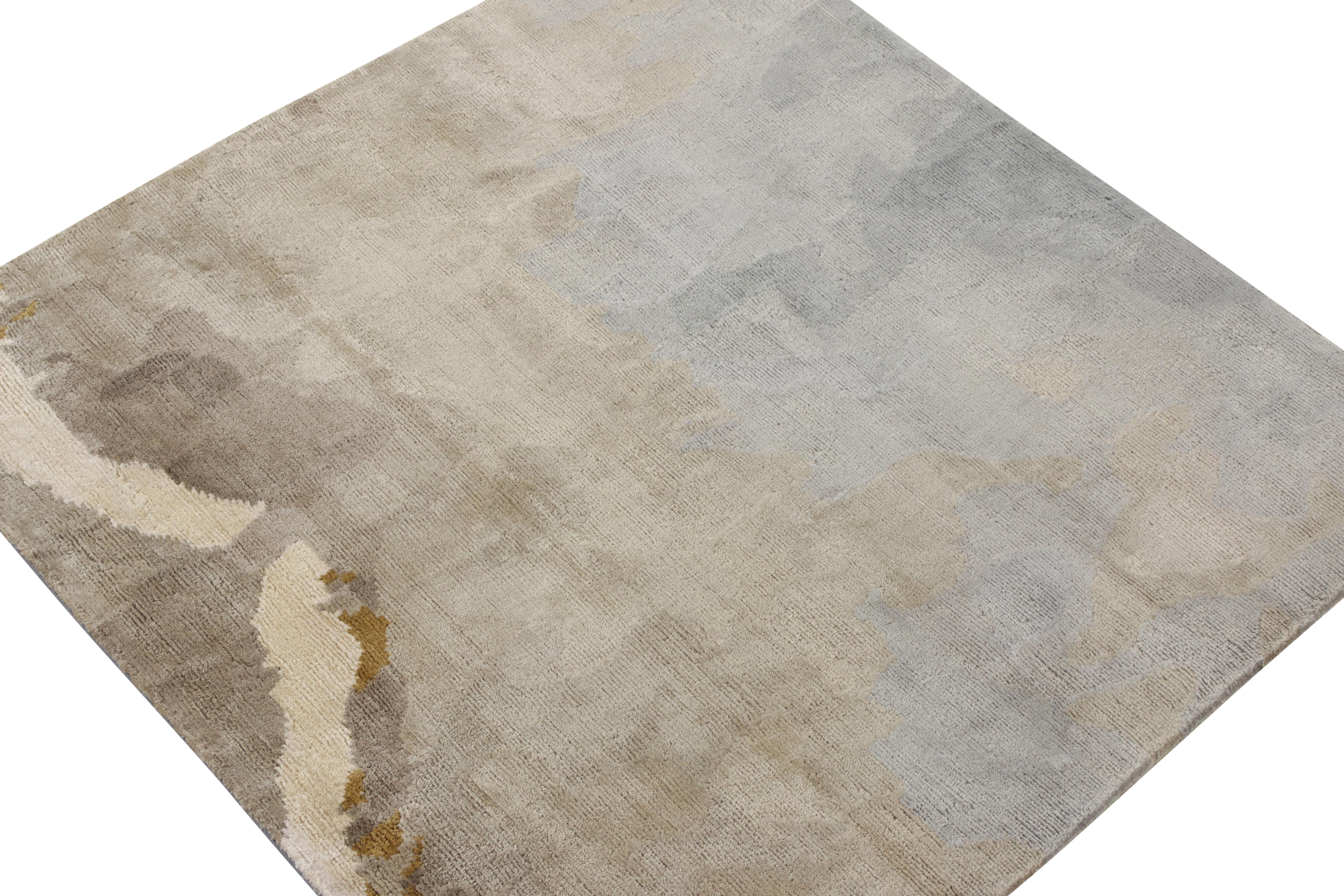 A square abstract accent rug from Rug & Kilim’s New & Modern Collection. The rug prevails in sophisticated tones of blue, silver-gray and off white juxtaposed by golden hints in the beige-brown background. The color tones ascend tastefully across