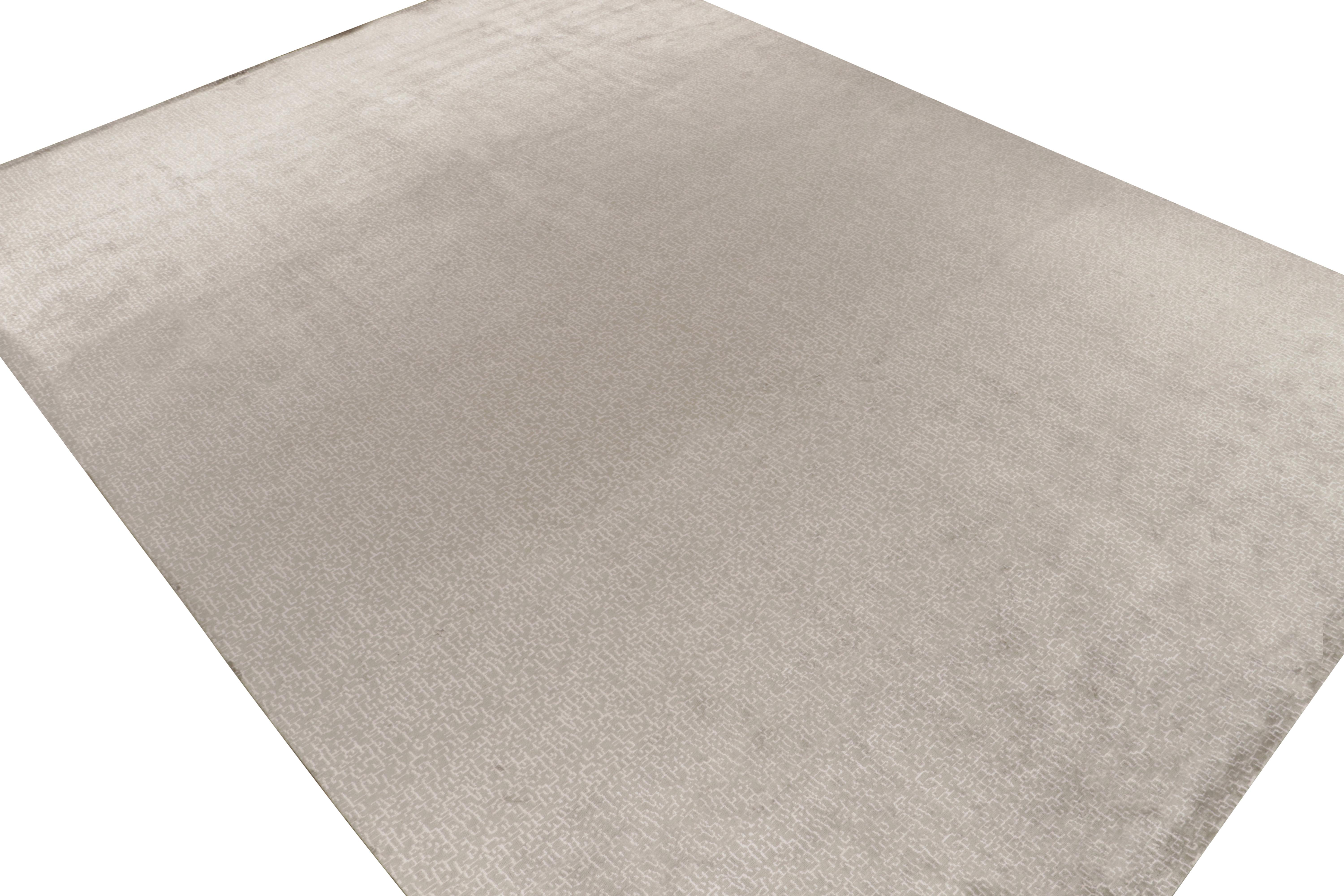 Rug & Kilim's präsentiert mit diesem maßgefertigten Teppichdesign eine neue, elegante Interpretation zeitgenössischer Ästhetik. Diese handgeknüpfte Wolldecke im Format 14x19 ist mit einem dezenten Muster in Weiß auf Silbergrau versehen und hat eine