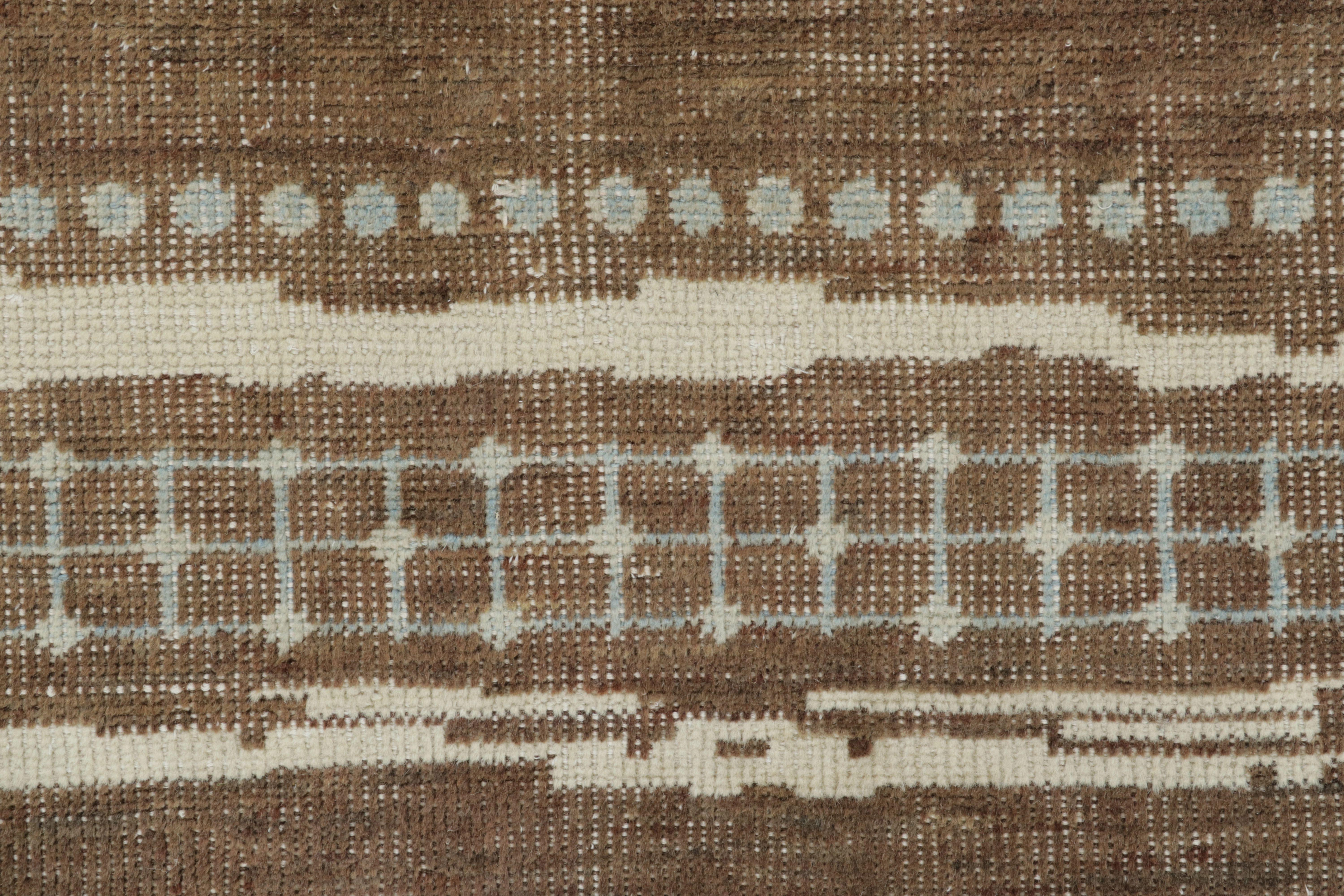 Questo magnifico tappeto 6x8 della Rug & Kilim's Moroccan Collection è un ricco pezzo di ispirazione marocchina, annodato a mano interamente in lana pregiata. Il disegno presenta un campo marrone sbiadito interrotto da bande di avorio cremoso che