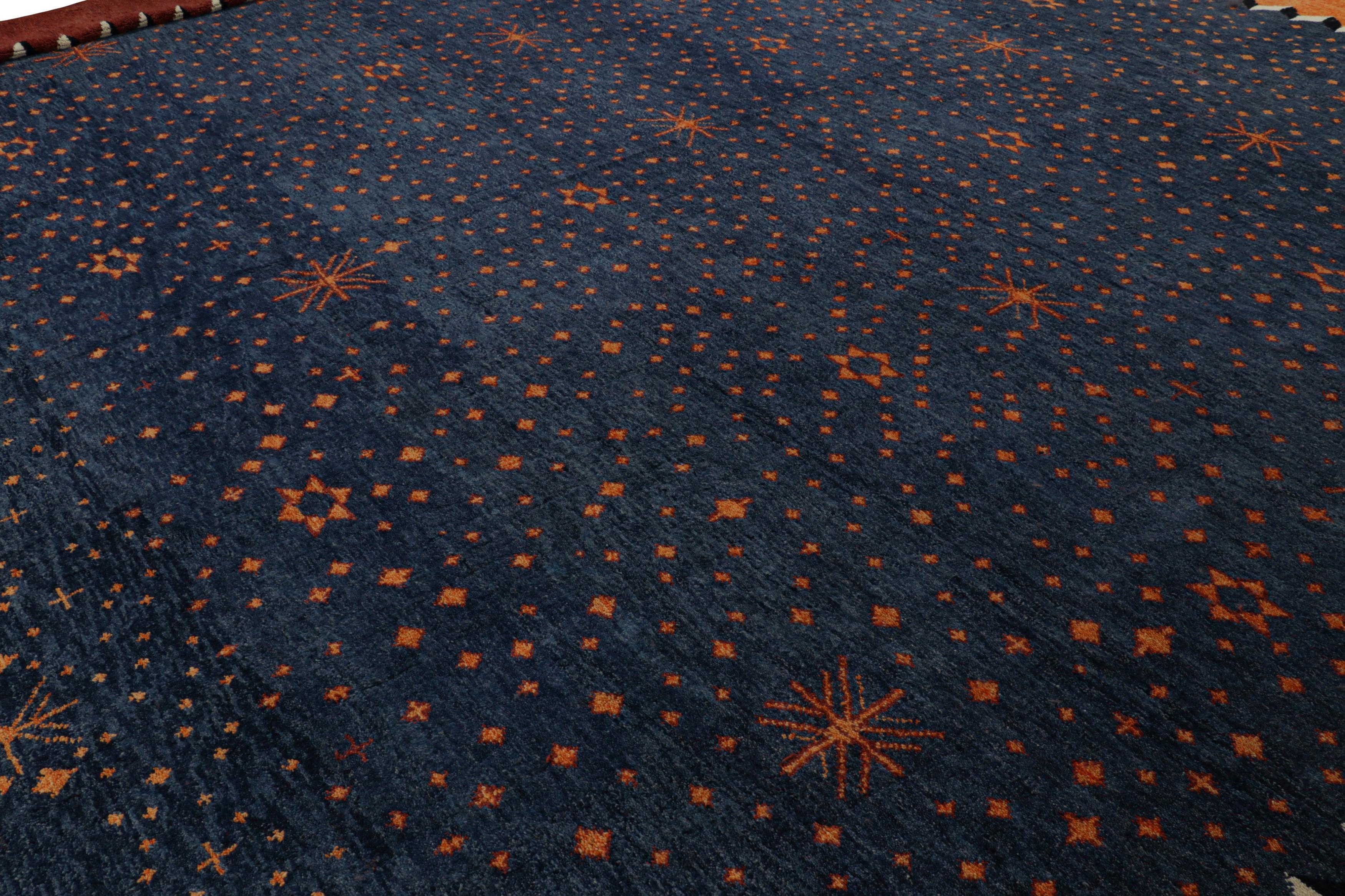 Made with hand-knotted wool and originating from Afghanistan, this 17x18 oversized contemporary Moroccan-inspired rug features a midnight-blue field with scattered star motifs in rust-orange tones framed by a rust-red border. 

On the Design: