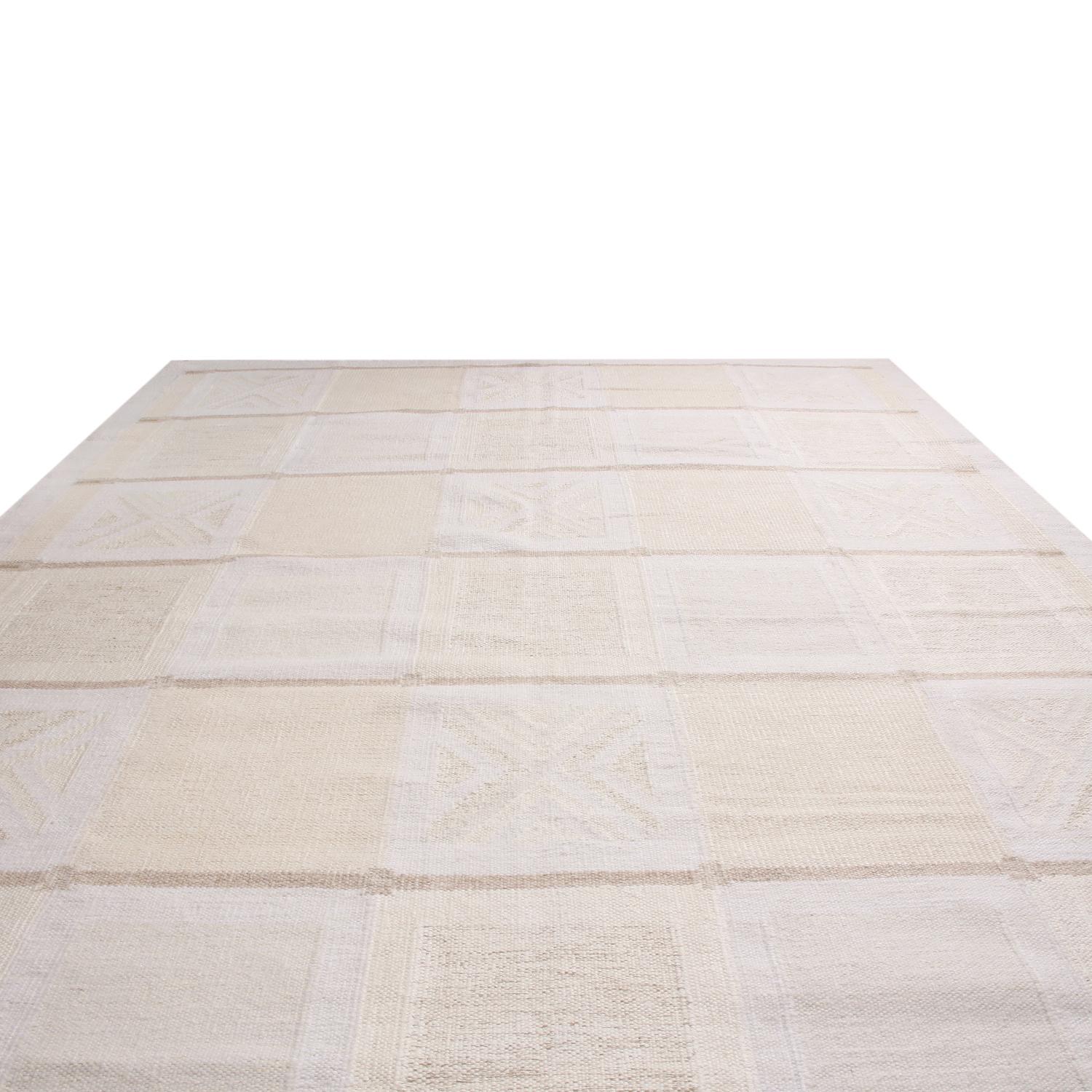 Originaire d'Inde, ce tapis à poils d'inspiration scandinave de la collection Rug & Kilim est noué à la main avec de la laine naturelle. Il présente un motif géométrique avec des rangées alternées de motifs tribaux encadrés par une bordure de garde