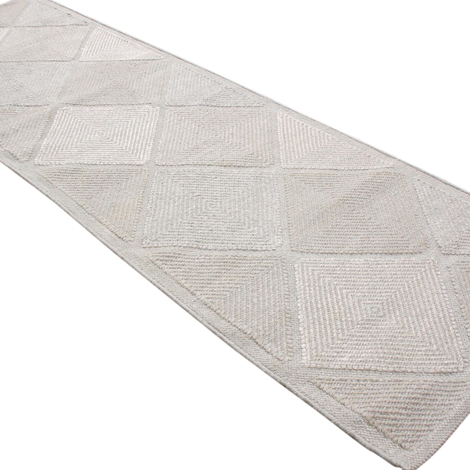 Dieser aus Indien stammende Teppich aus natürlichem Polyester stammt aus der skandinavischen Outdoor-Kollektion von Rug & Kilim, die unter anderem diese gewellte Interpretation berühmter marokkanischer Rautenmuster in mehrfarbigen cremeweißen und