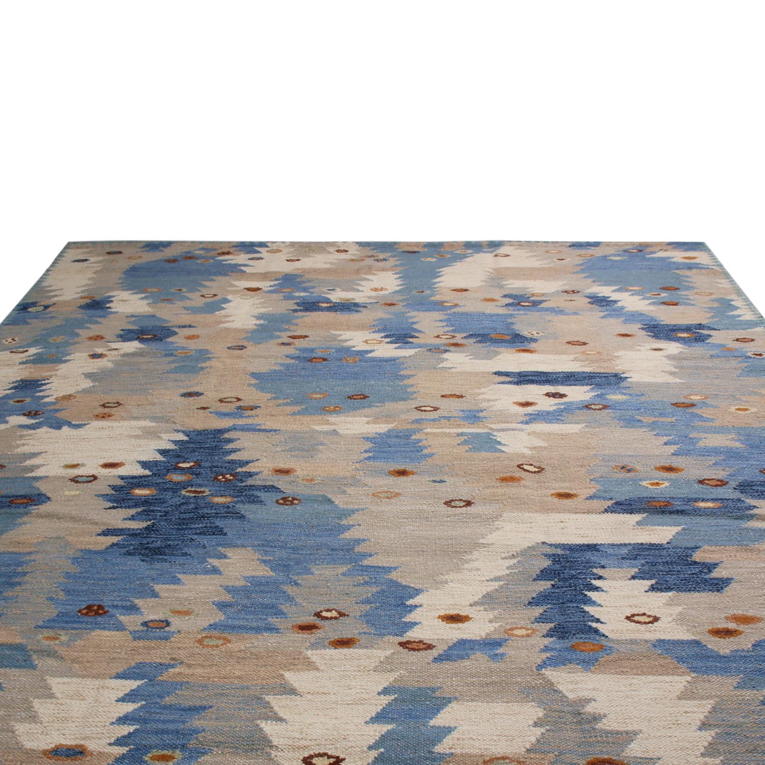 Originating from India, this hand knotted pile rug hails from Rug & Kilim’s Scandinavian-inspired collection, featuring a distinct tribal geometric all-over field design in multi-tonal blue colorway with luminous brown accents; highlighted by