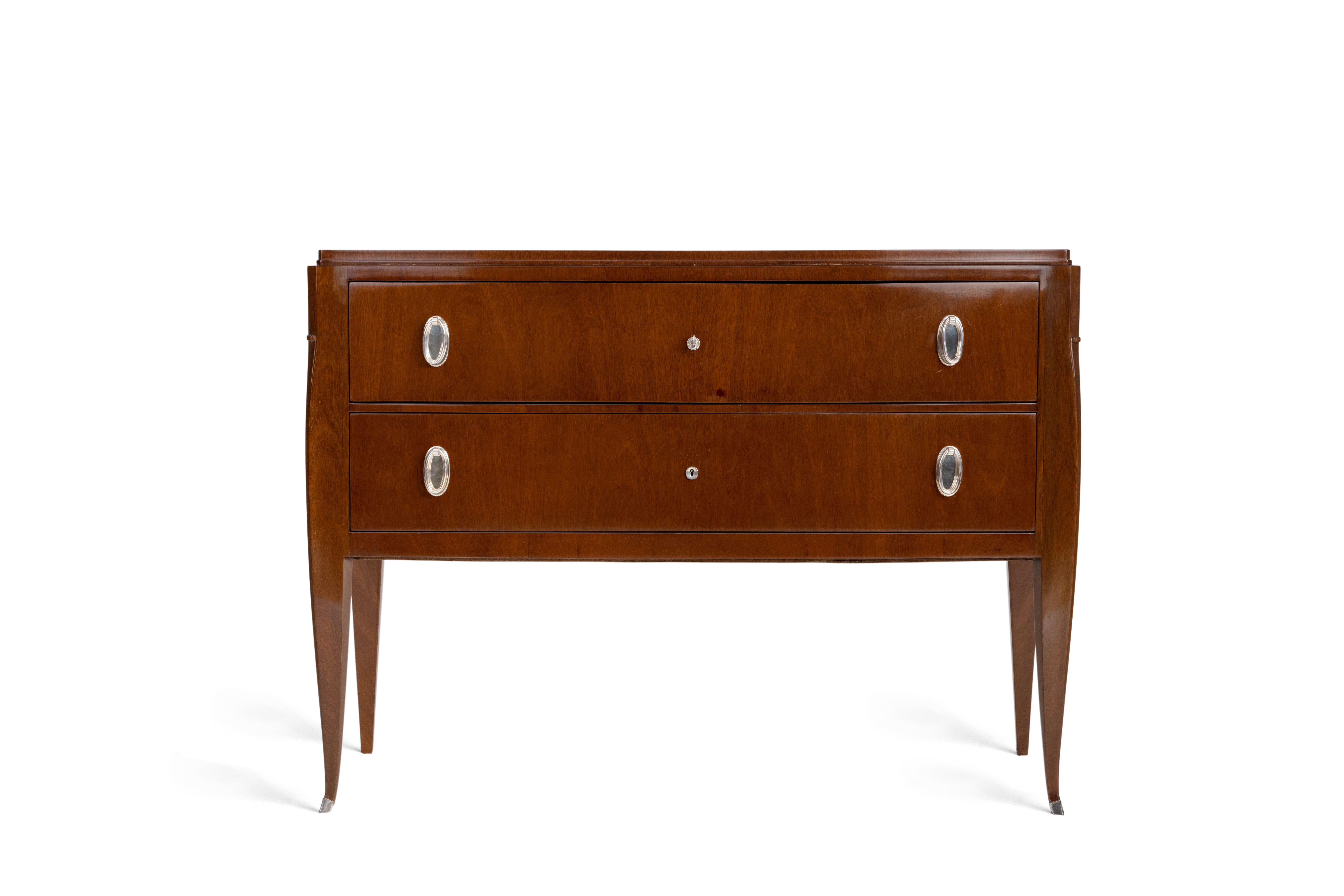 Commode modèle 'Colette' en amarante massif et placage d'amarante, de forme galbée à deux tiroirs en façade ouvrant par des poignées de préhension en bronze argenté. Le sommet est souligné par un listel de section carrée. Porté par quatre pieds