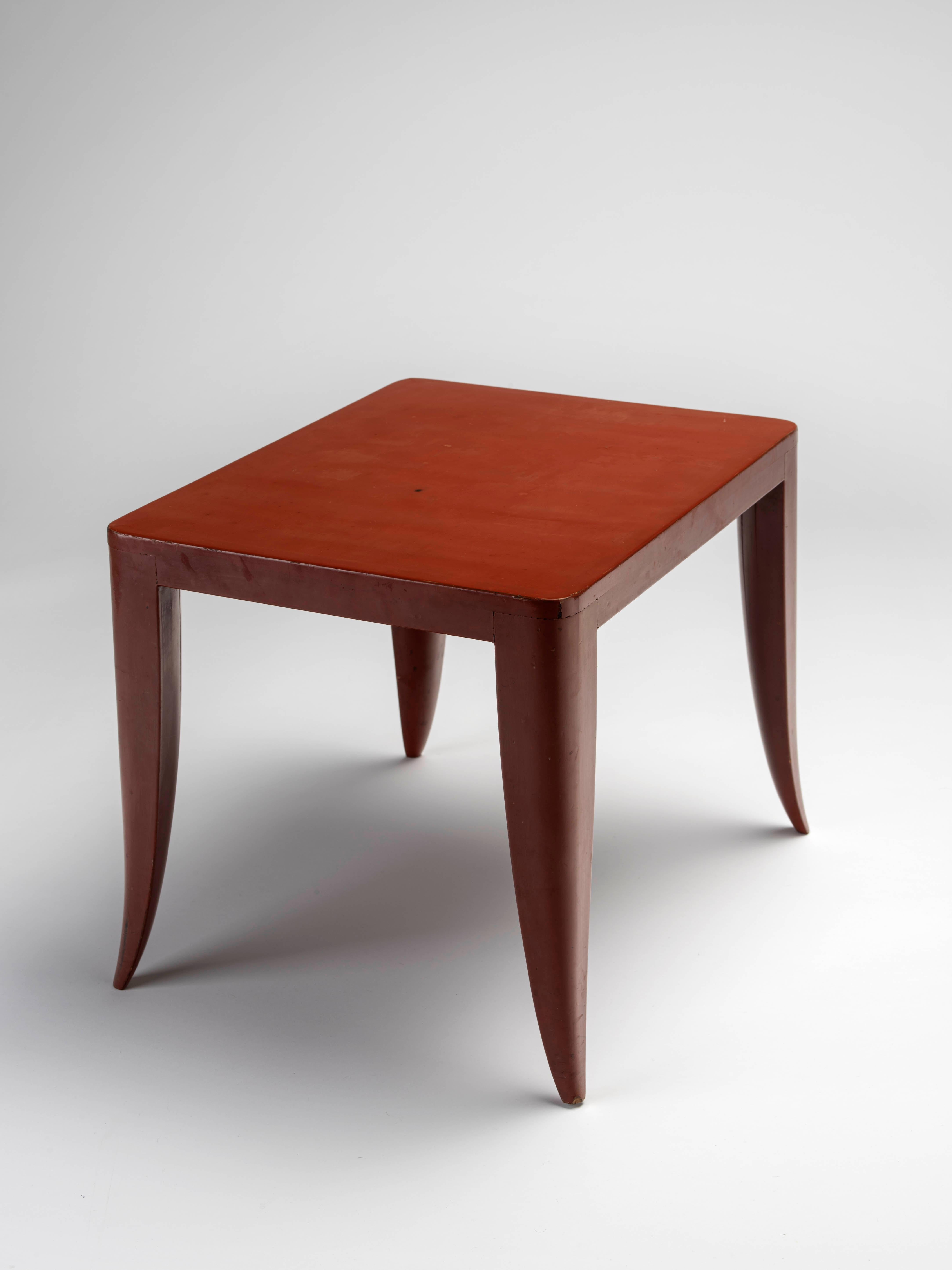 Red lacquered ‘Ducharne Volante’ coffee table with a rectangular top and tapered, saber-shaped legs. This table is a part of a series of two nesting tables created by Ruhlmann for François Ducharne. The table is lacquered by Jean Dunand. Reference