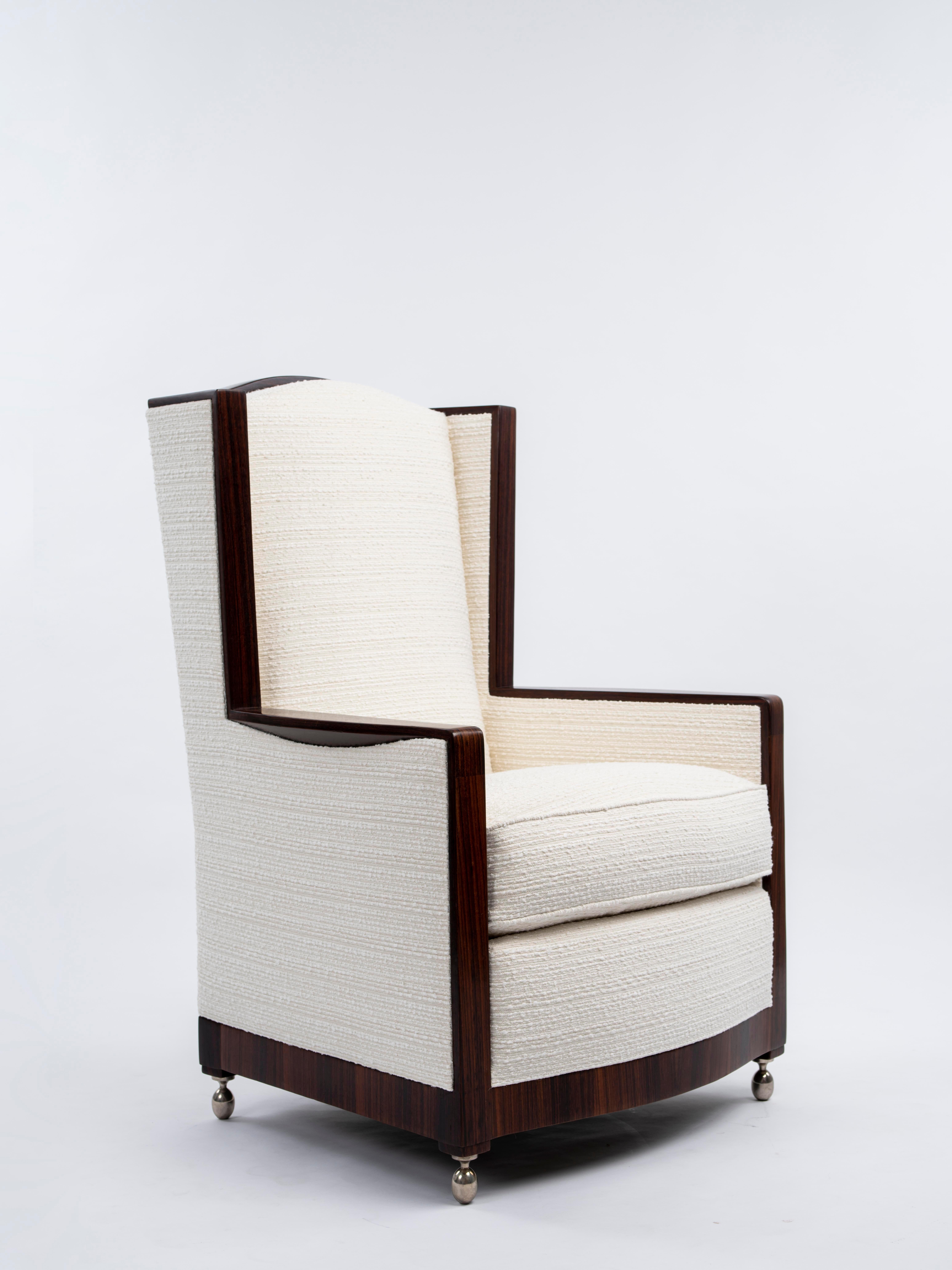 The pair of “Ear Cuffed” Bergères made from Indian rosewood. The armchairs feature a gracefully curved backrest framed by two ear-like extensions. The flattened armrests are designed with cuffs and rest on four silvered bronze ball feet. The