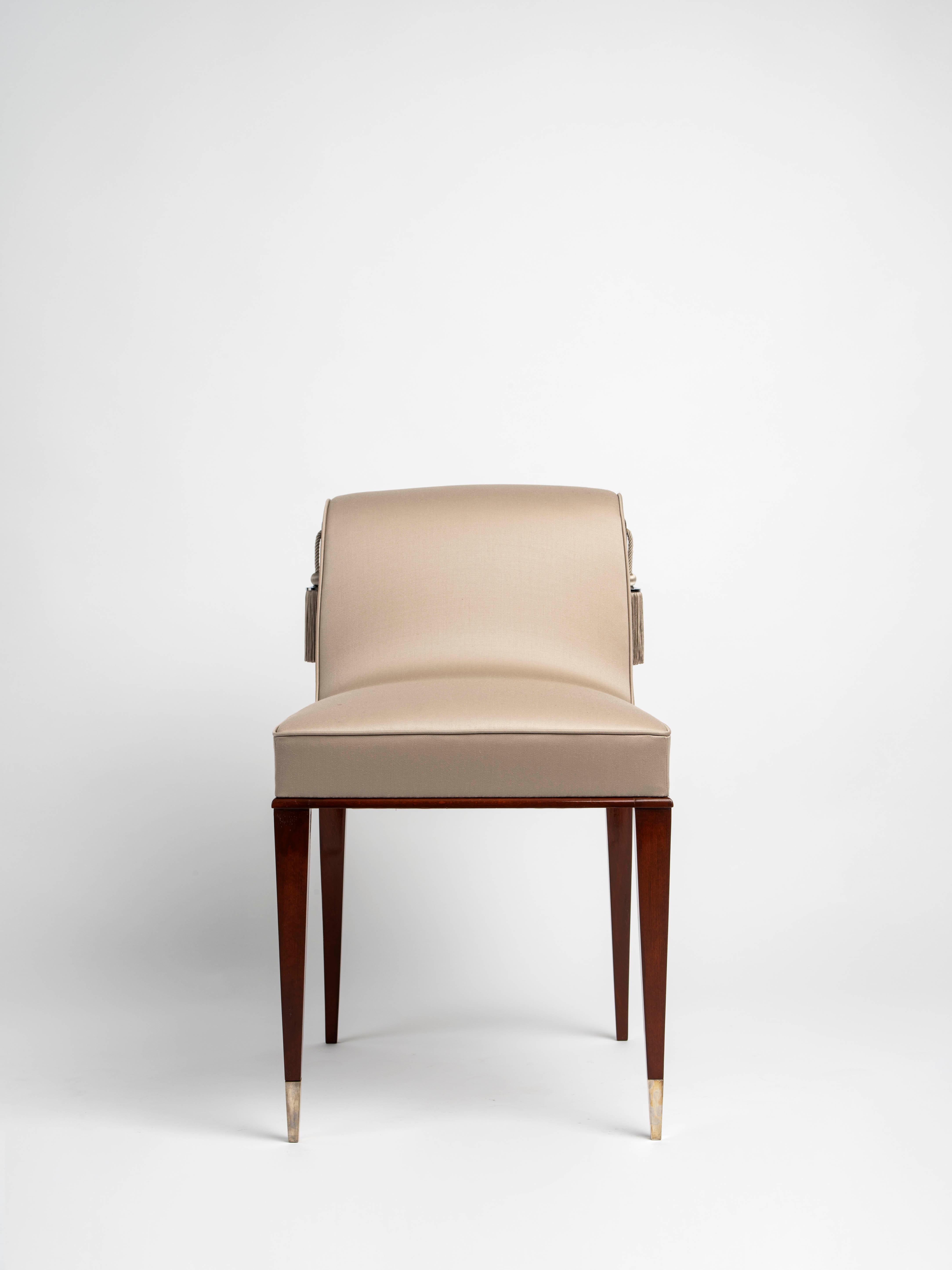 Rare mahogany dressing chair with an extended seat and a short, curved back adorned with trim. The front legs are wrapped and capped in silvered bronze, the back legs are curved. A variant of the Tauzin boudoir chair model No. 3 AR from the artist’s