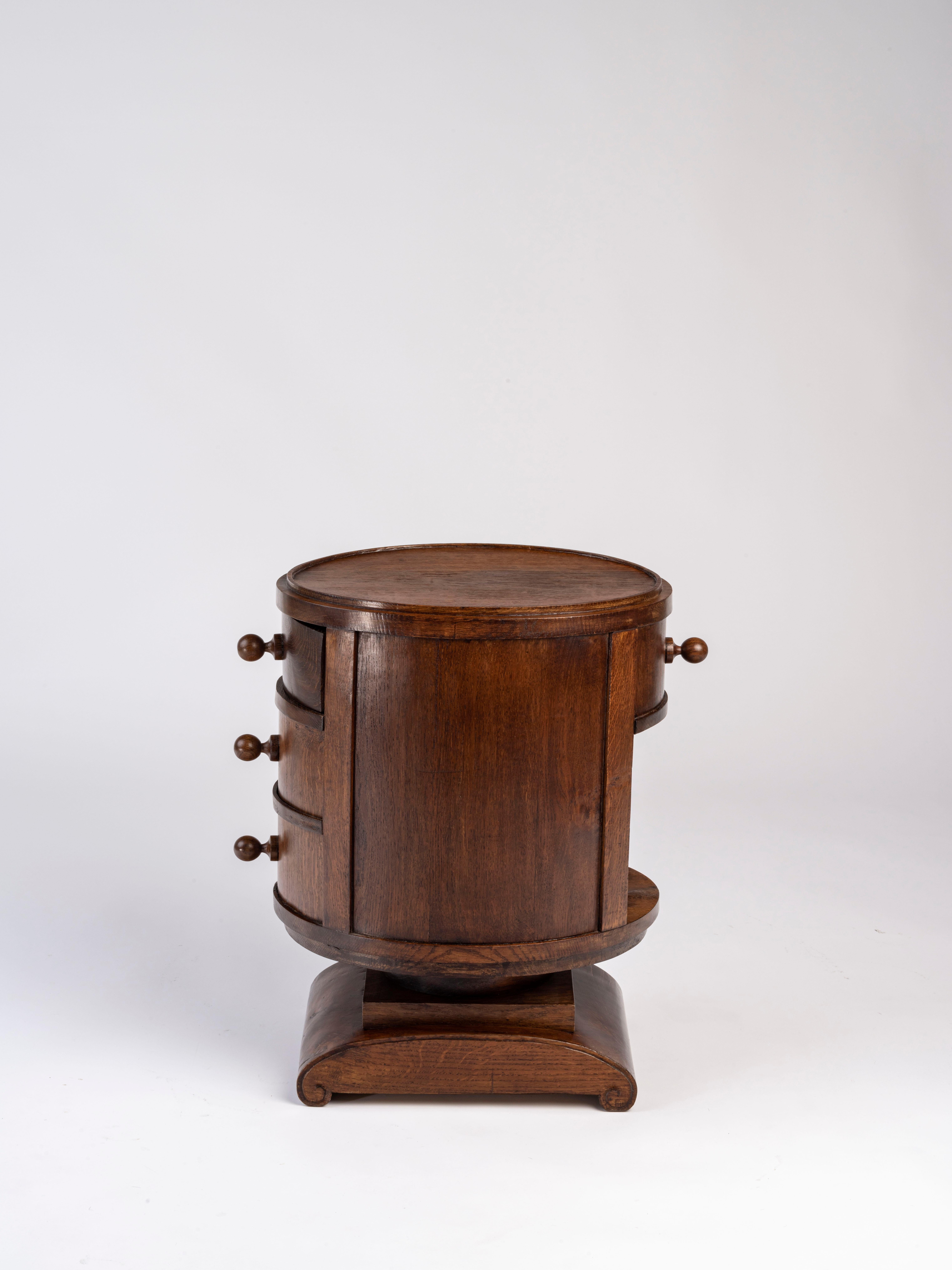 “Tournecol” side table or nightstand in solid oak and oak veneer 
with an oblong shape, open compartment, and drawers resting on a roller base. Stamped 'Ruhlmann'. 
Reference number 1009AR and 1049NR in the Ruhlmann Archives,
Musée des Années 30,