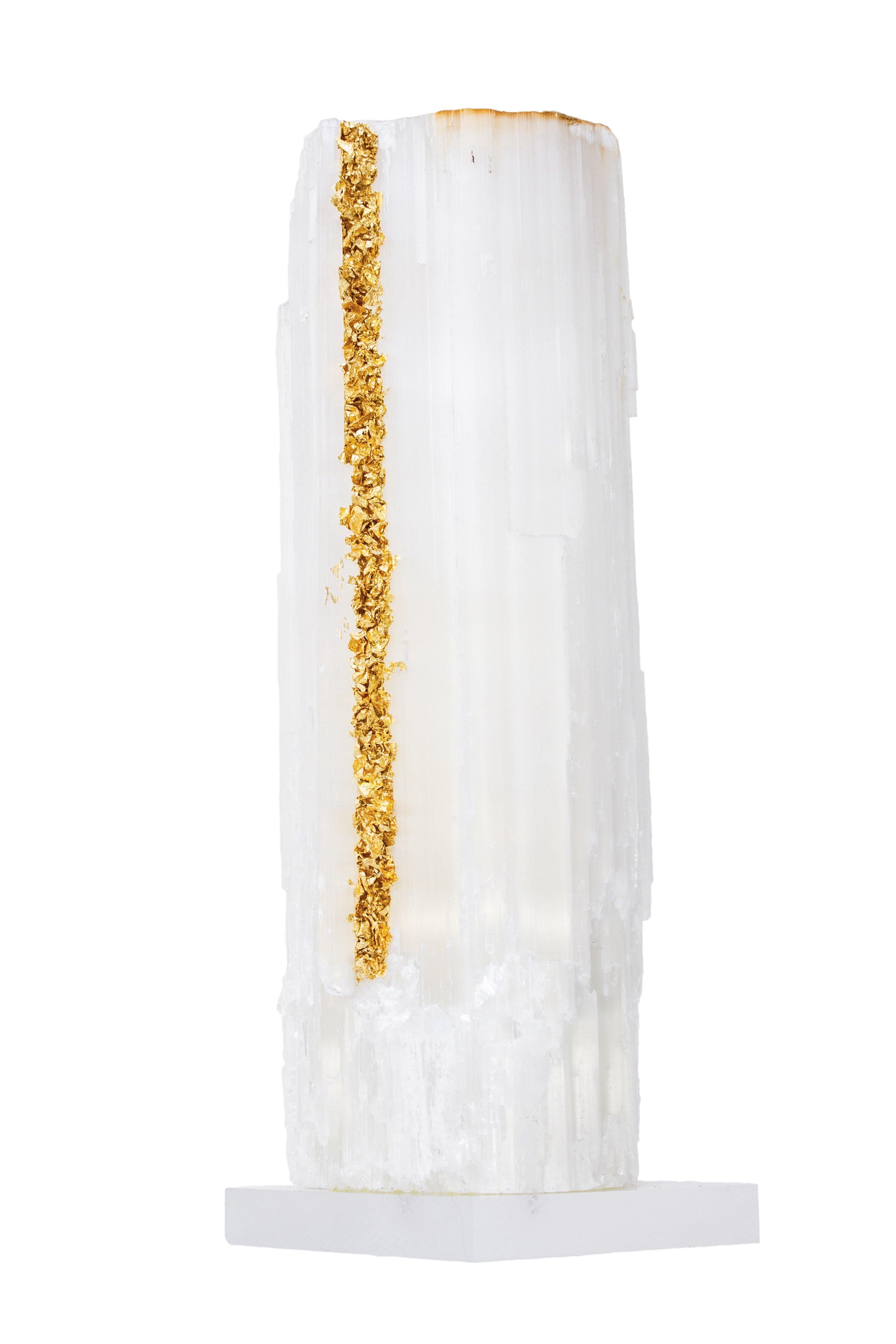 Ruler selenite with gold leaf on a Lucite base. Ruler selenite is made up of single, prismatic selenite crystals from Morocco that were formed in extensive beds by the evaporation of ocean brine. This mineral is characterized by a silky, pearly