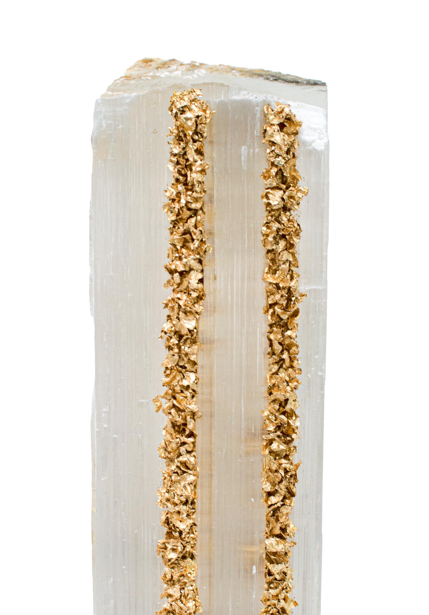 Ruler Selenite with gold leaf on a Lucite base. Selenite logs are single, prismatic selenite crystals from Morocco that were formed in extensive beds by the evaporation of ocean brine. This mineral is characterized by a silky, pearly luster called