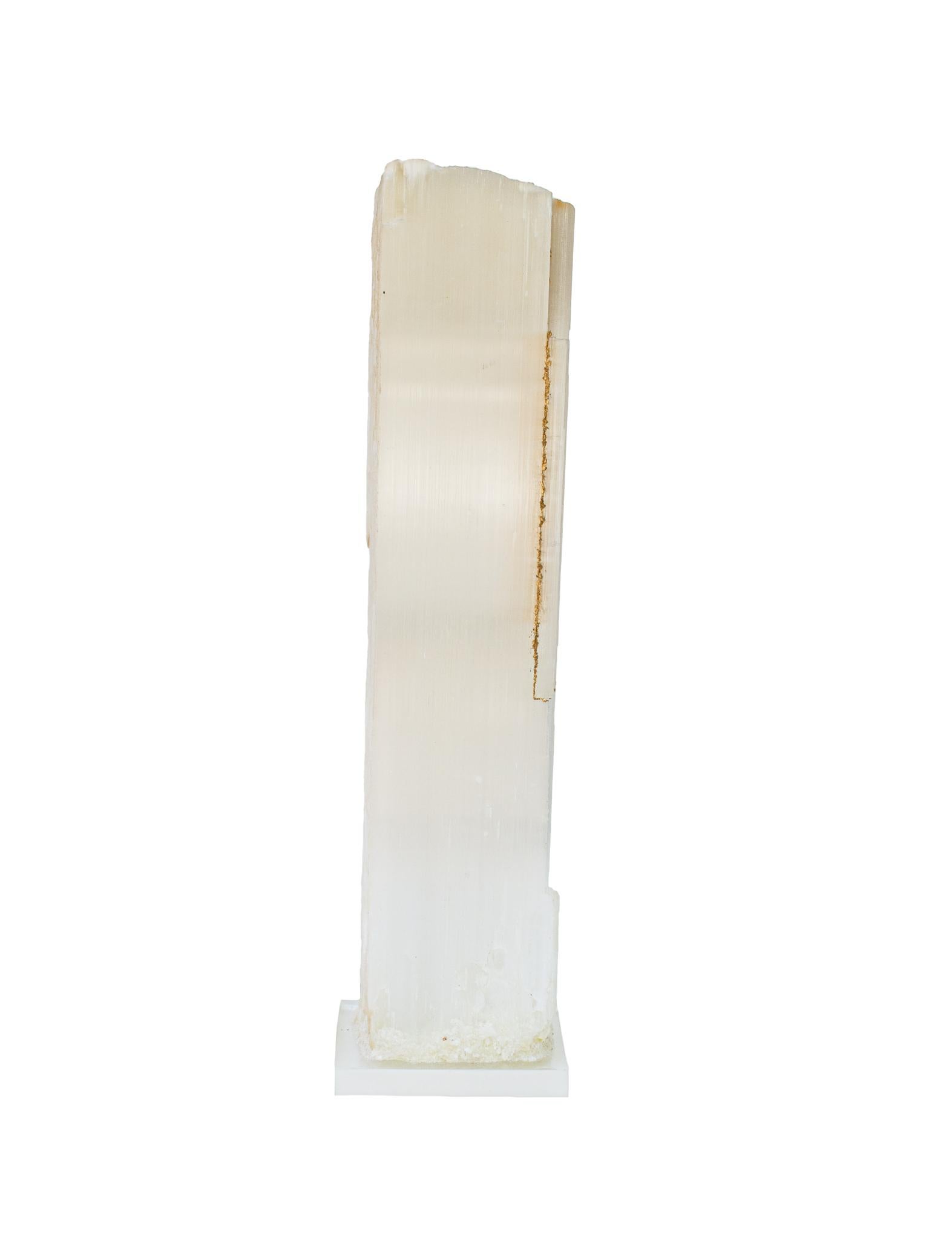 Ruler Selenite with gold leaf on a Lucite base. Selenite logs are single, prismatic selenite crystals from Morocco that were formed in extensive beds by the evaporation of ocean brine. This mineral is characterized by a silky, pearly luster called