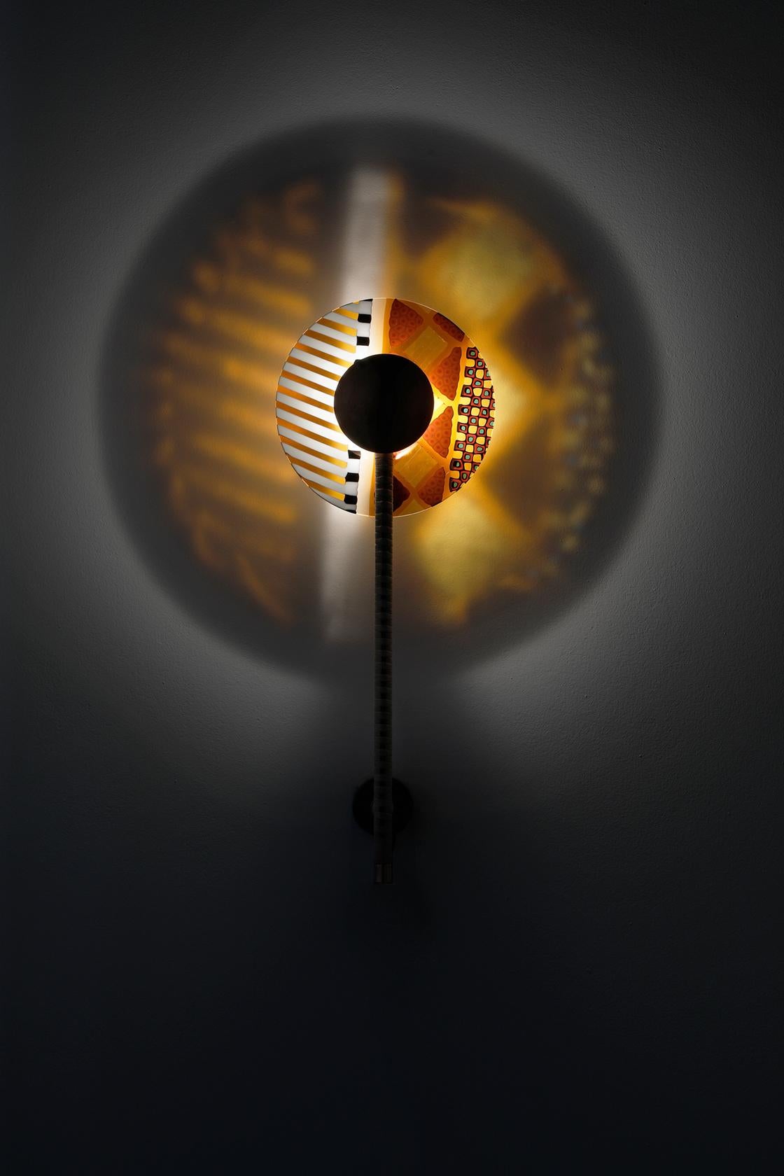 Italiano Rullo, lampada da parete a LED composta da uno stelo in ottone rivestito e da un disco di vetro colorato in vendita
