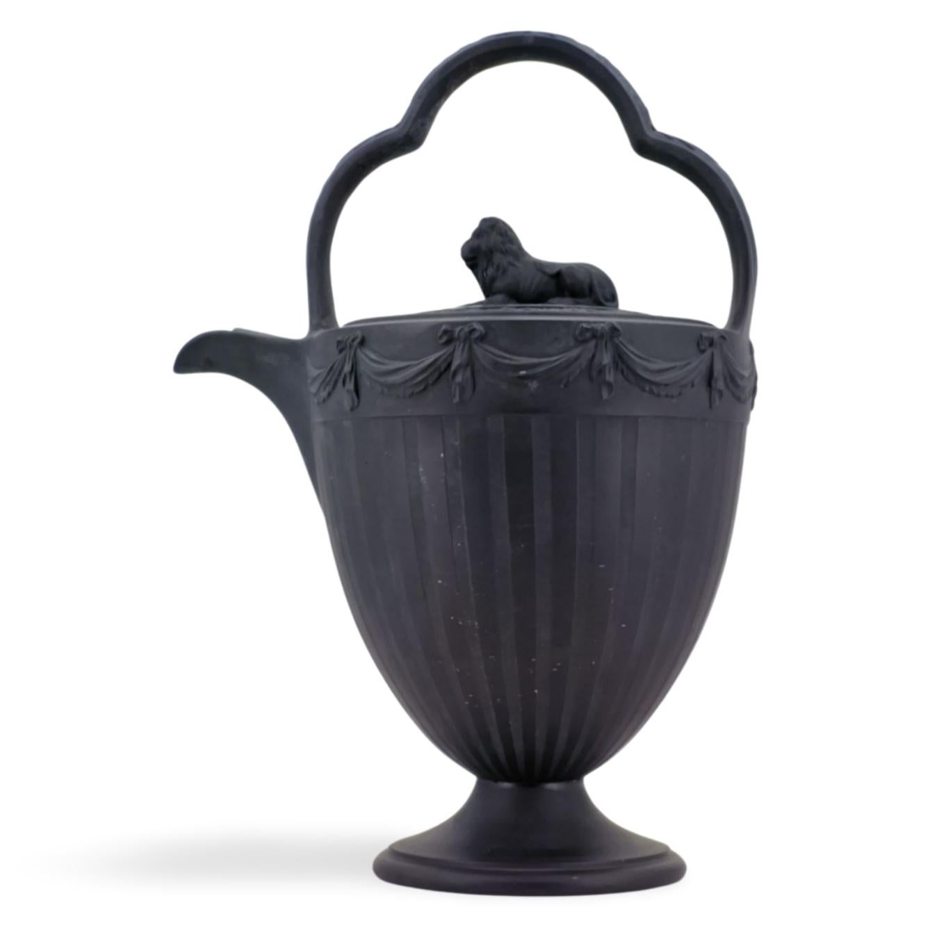 Un eccellente bollitore per rum in basalto nero, con decorazioni tornite a motore e festoni applicati. Il terminale a forma di leone è ben posizionato sotto il manico a tre archi.

I bollitori di rum venivano utilizzati per servire acqua calda da