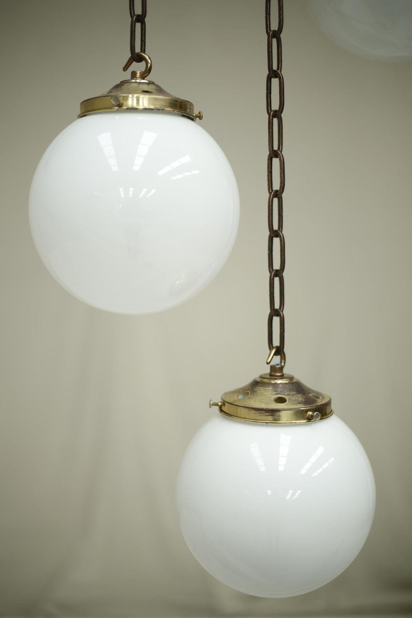 These are very attractive 20th century opaline globe lights. They are a wonderful smaller than average size giving them the ability to be used in a number of different ways. Either in a run over a kitchen island or in a bunch hanging as a