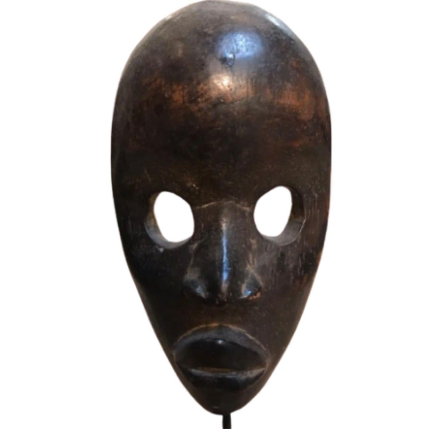 Diese hölzerne Gonveia-Maske ist nach der Tradition des Danh-Stammes handgefertigt.

Die Maske steht auf einem Eisenständer.