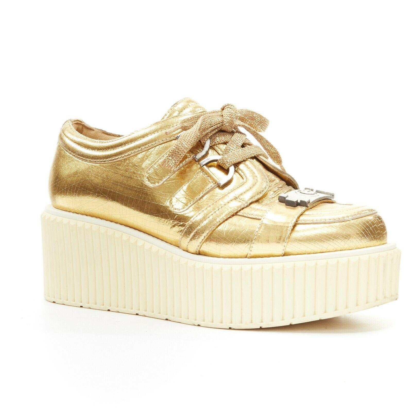 runway CHANEL metallic gold foil leather strapped toe platform creeper EU36
CHANEL
Gold metallic foil leather upper. Tonal stitching. 
Matte silver-tone metal hardware. CC logo strap at toe. 
Lace up closure. Tonal stitching. Round toe. 
Cream