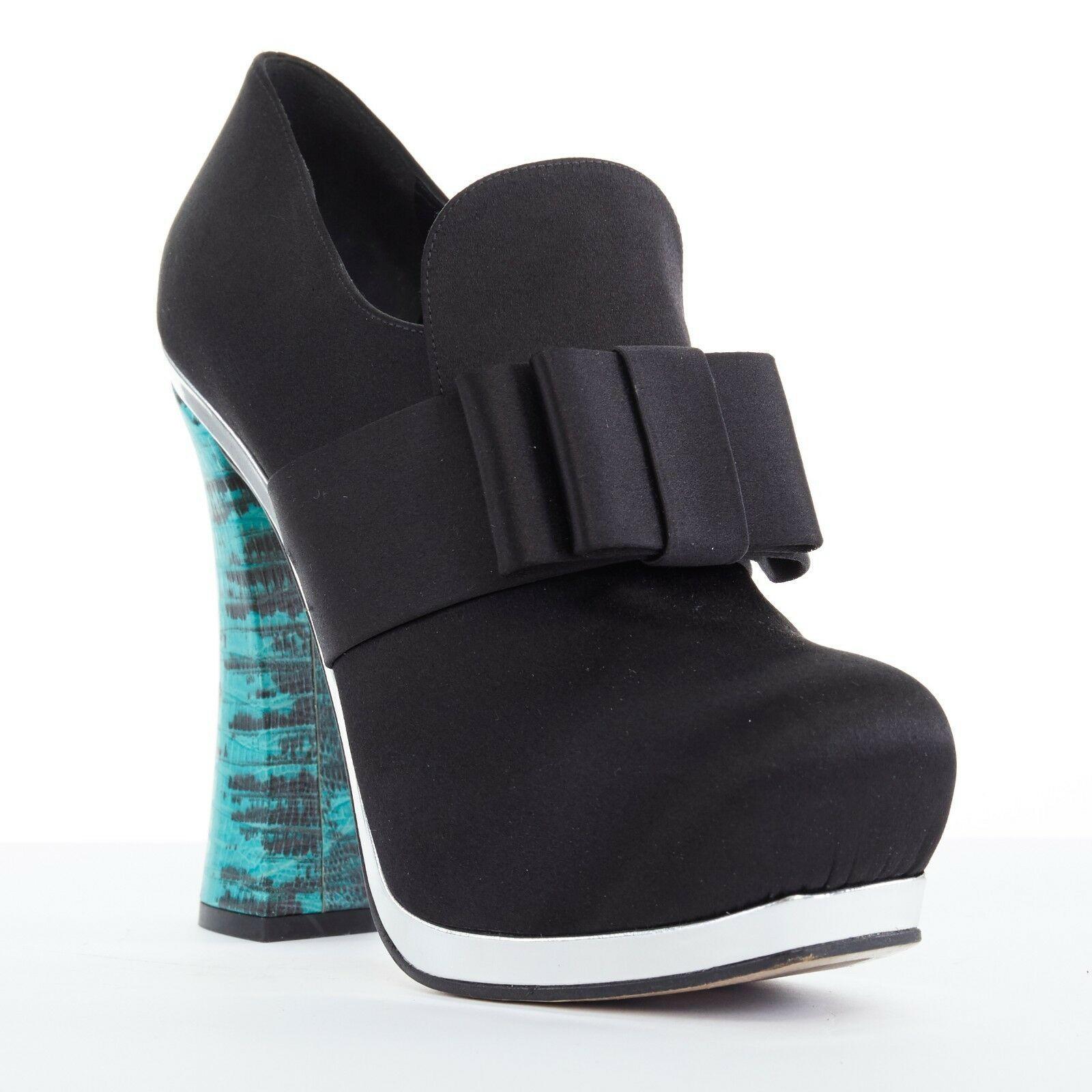 runway MIU MIU black satin bow silver platform blue curved heel bootie heel EU37
MIU MIU
Black satin upper. Signature Miu Miu origami bow design front. 
Rounded toe. Concealed platform. Silver leather trimming along outsole. 
Turquoise blue stamped